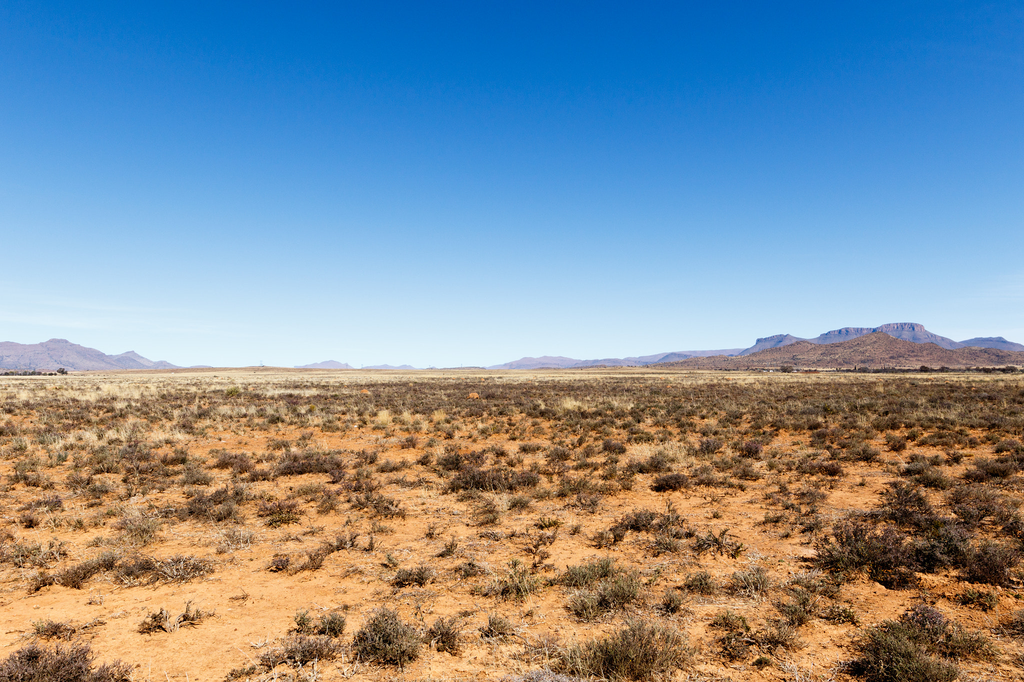 Canon EF 300mm f/2.8L sample photo. Barren field with mountains and blue sky photography