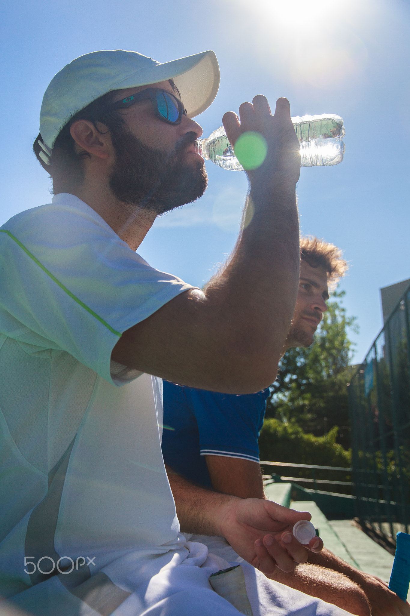 Two professional players hydrating after a hard game of tennis