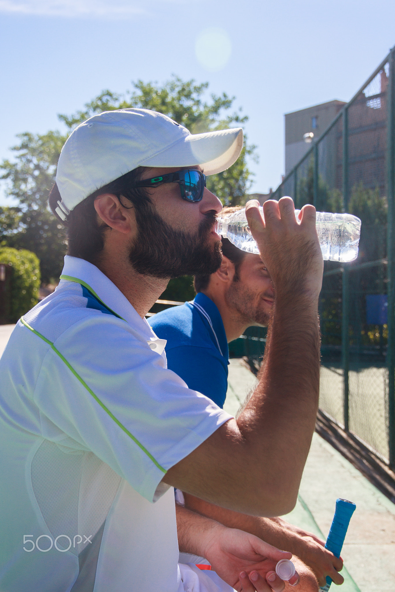 Two professional players hydrating after a hard game of tennis