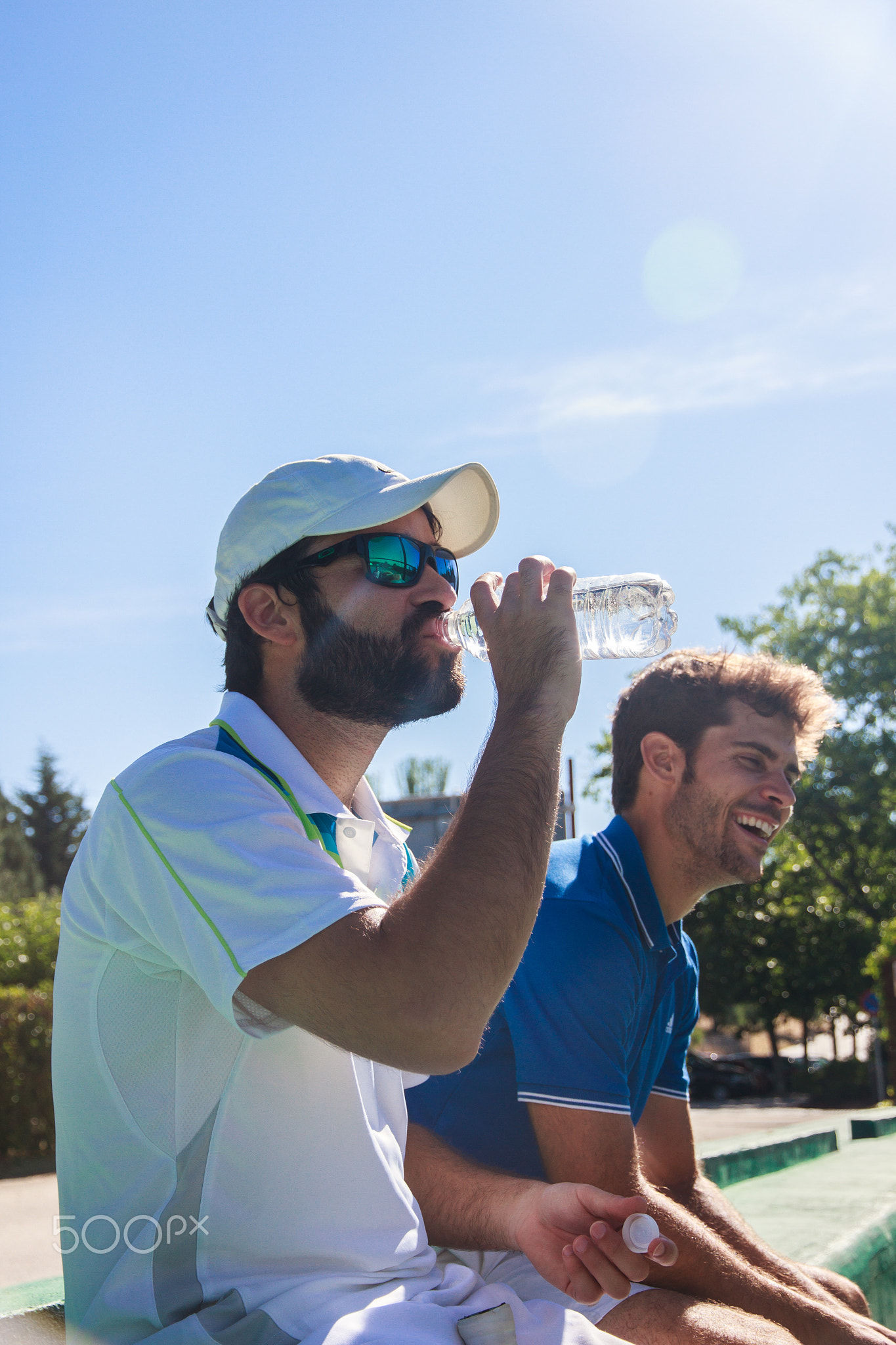 Two professional players hydrating after a hard game of tennis