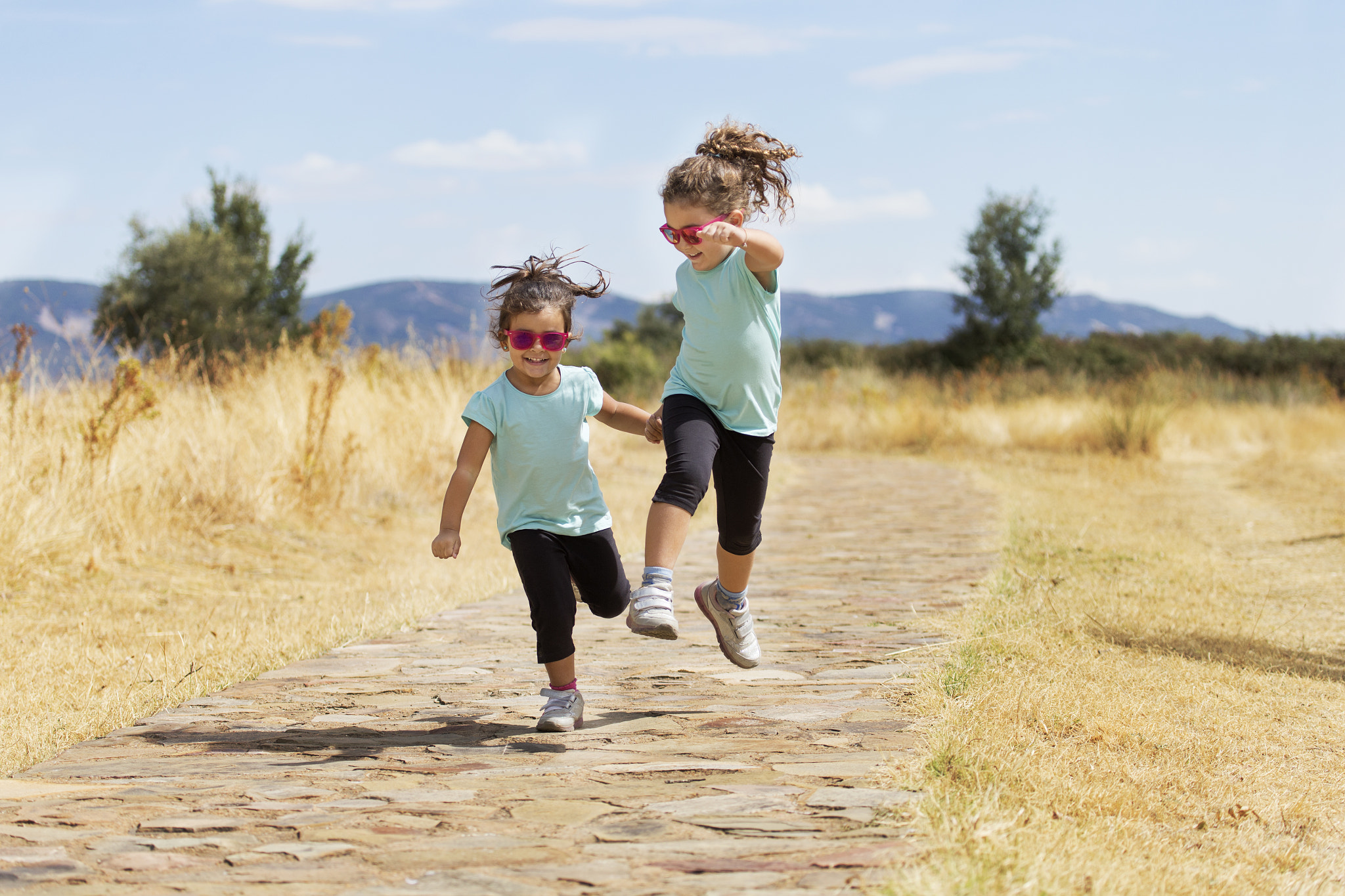 Canon EF 100-400mm F4.5-5.6L IS USM sample photo. Lovely twins jumping along path in countryside photography