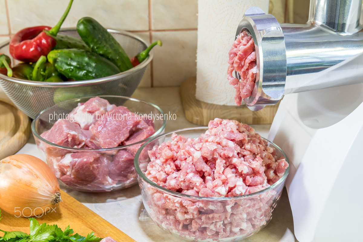 Home electric meat-grinder is making pork stuffing