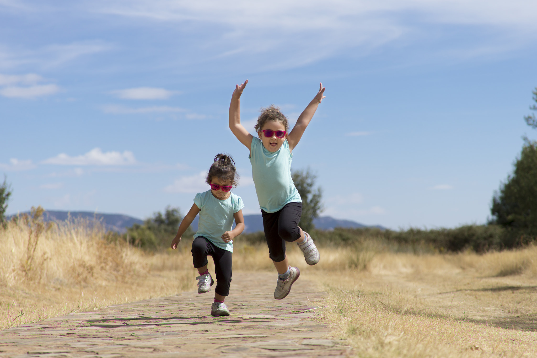 Canon EF 100-400mm F4.5-5.6L IS USM sample photo. Lovely twins jumping along path in countryside photography