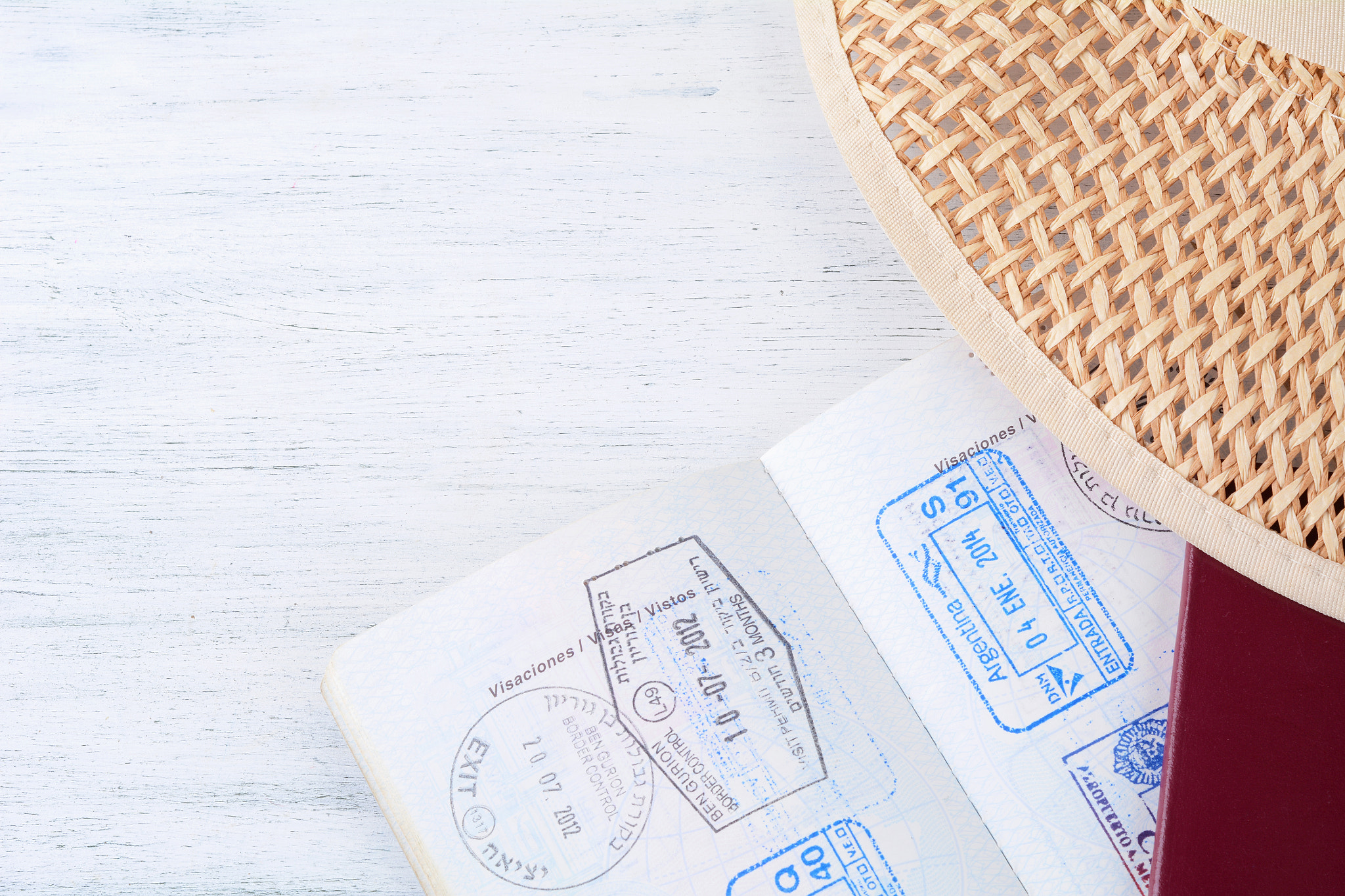 Open passport with visa stamps and hat.