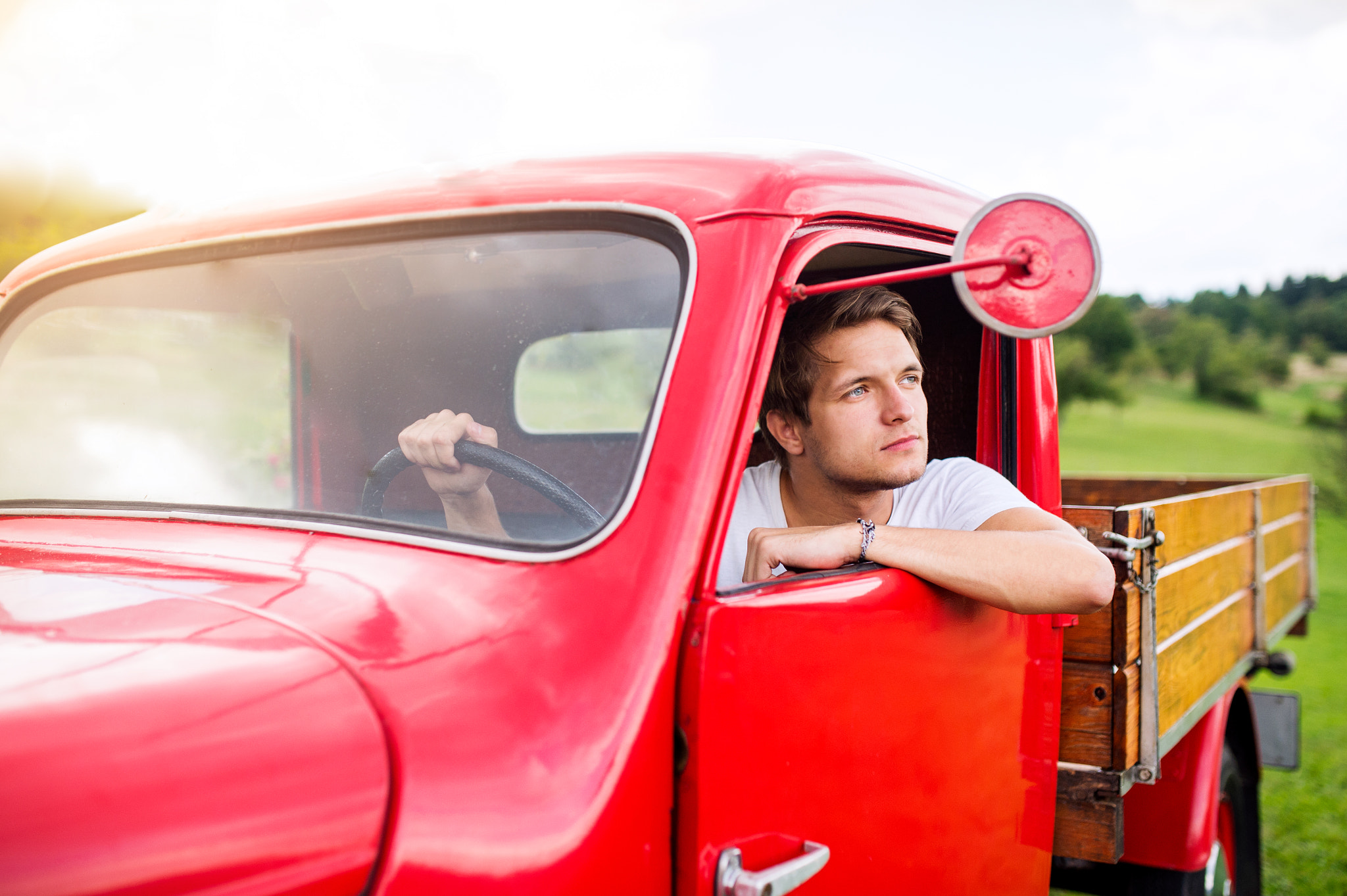 Nikon D4S + Sigma 35mm F1.4 DG HSM Art sample photo. Young man inside red vintage pickup truck, green nature photography