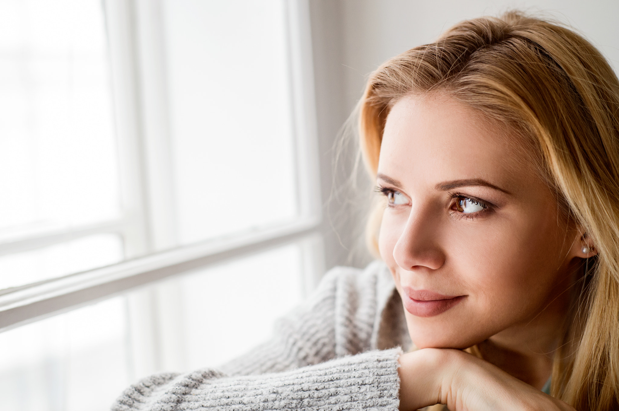 Woman sitting on window sill, looking out of window