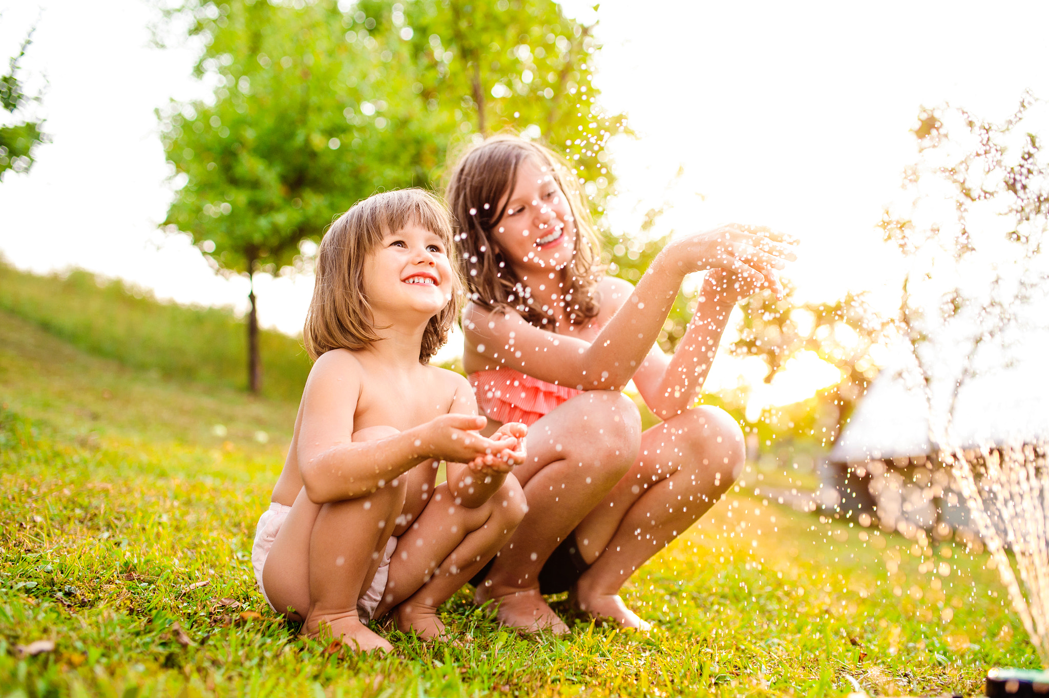 Nikon D4S + Sigma 35mm F1.4 DG HSM Art sample photo. Two girls at the sprinkler, sunny summer in the garden photography