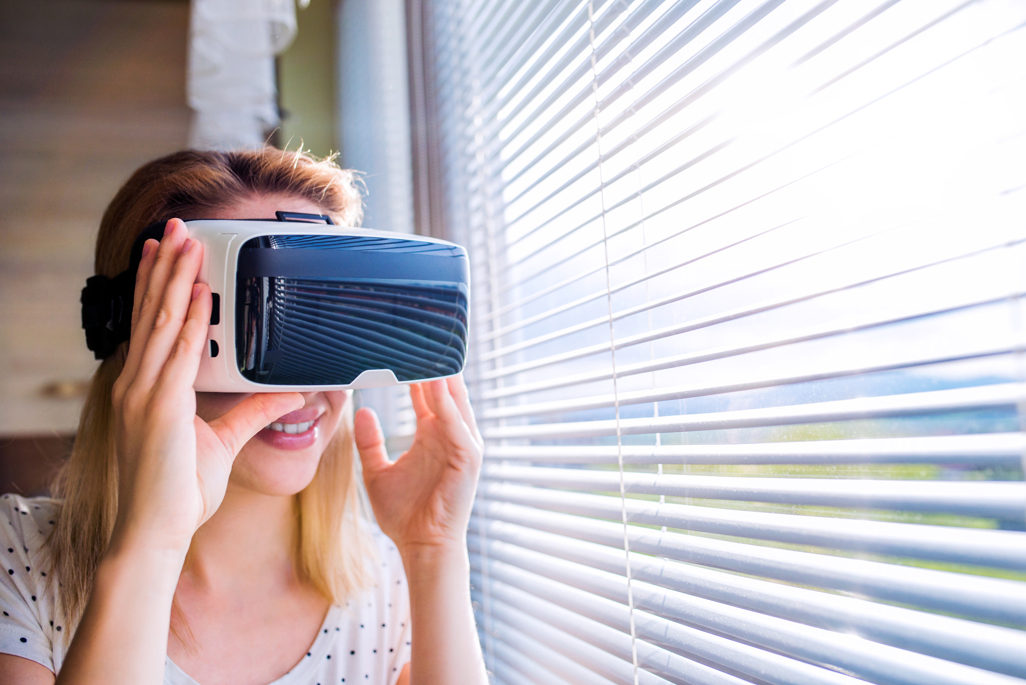 Woman wearing virtual reality goggles standing in a kitchen