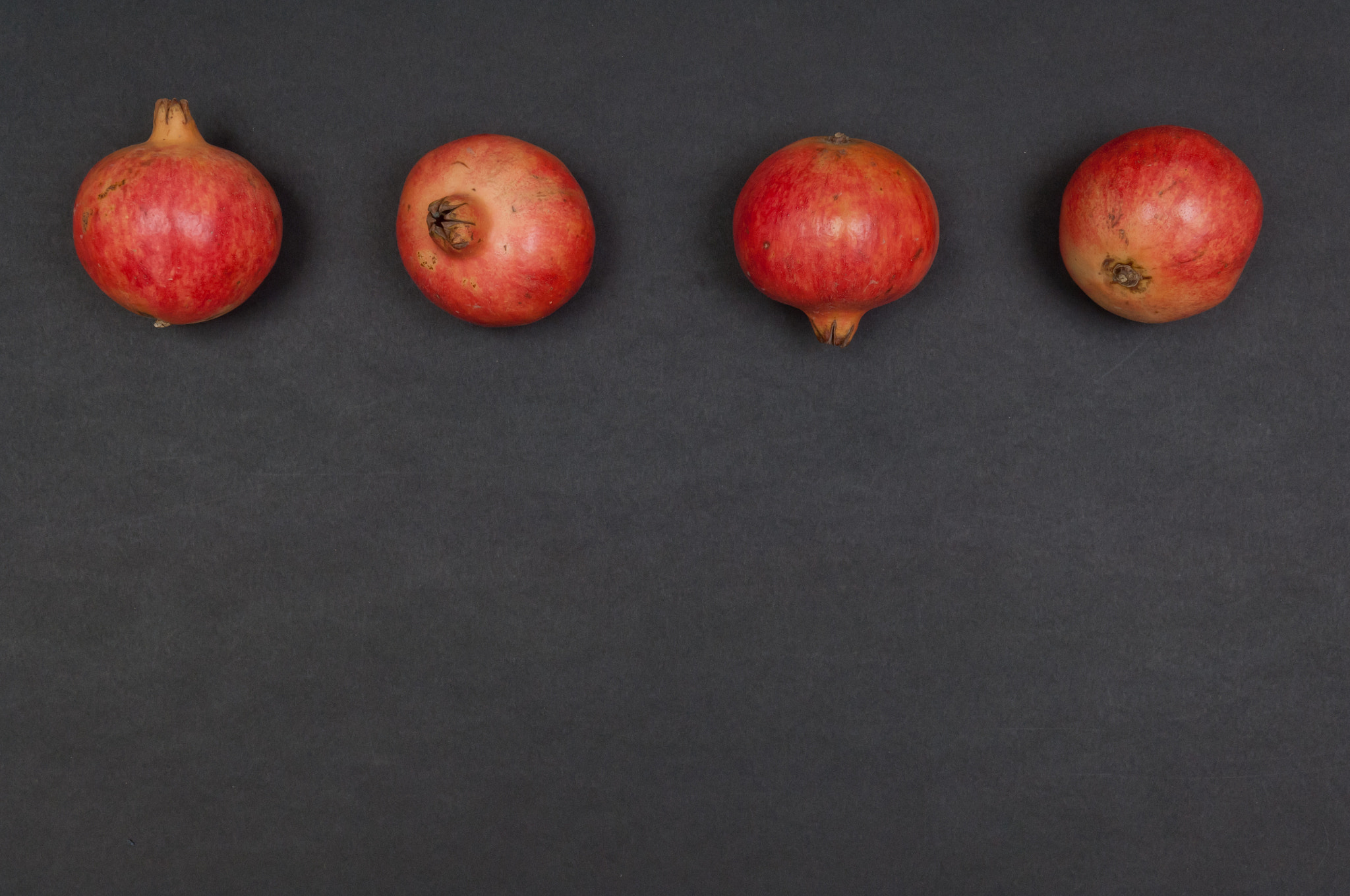 Nikon D2X sample photo. Whole ripe pomegranates in a row on dark grey background photography