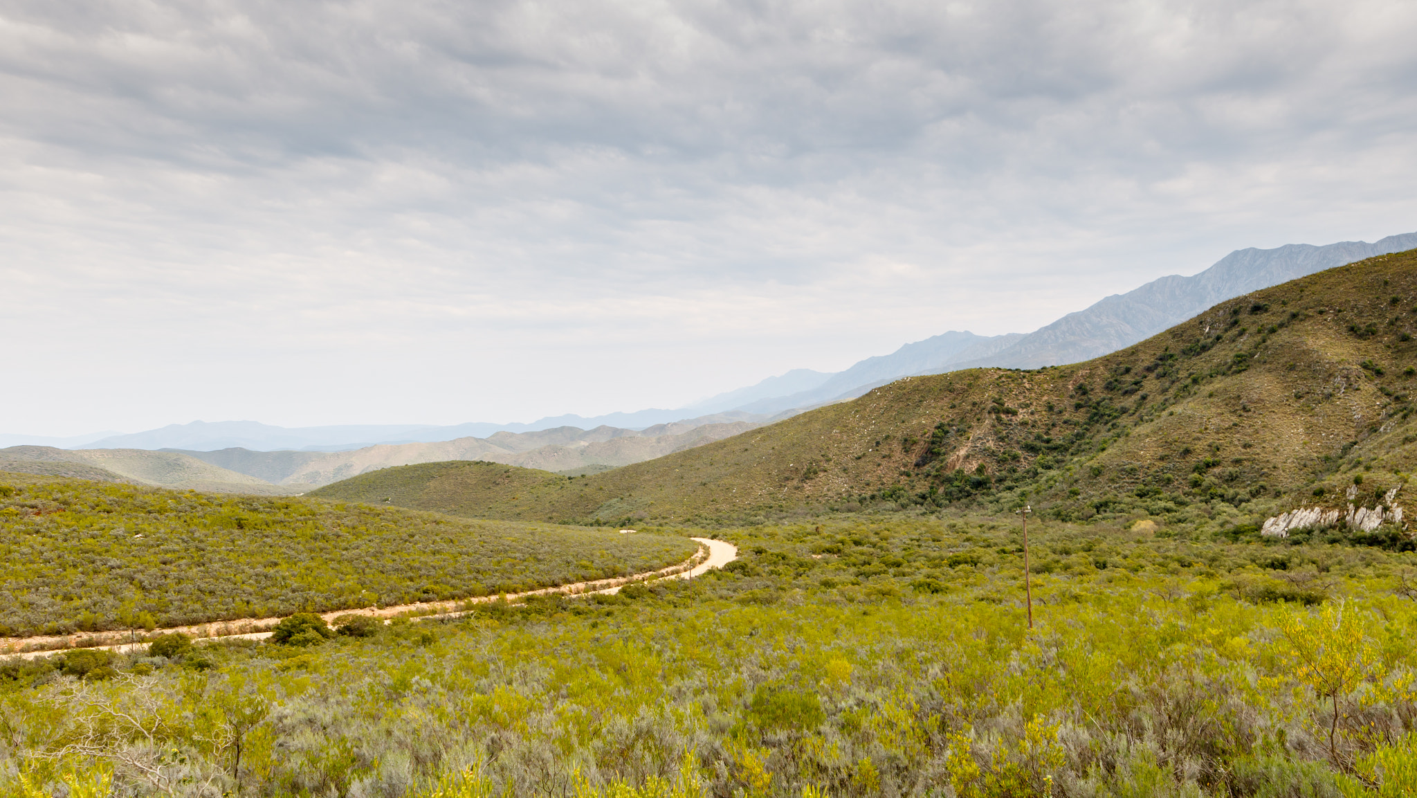 Canon EF 300mm f/2.8L sample photo. Green valley with road leading thru the mountains photography