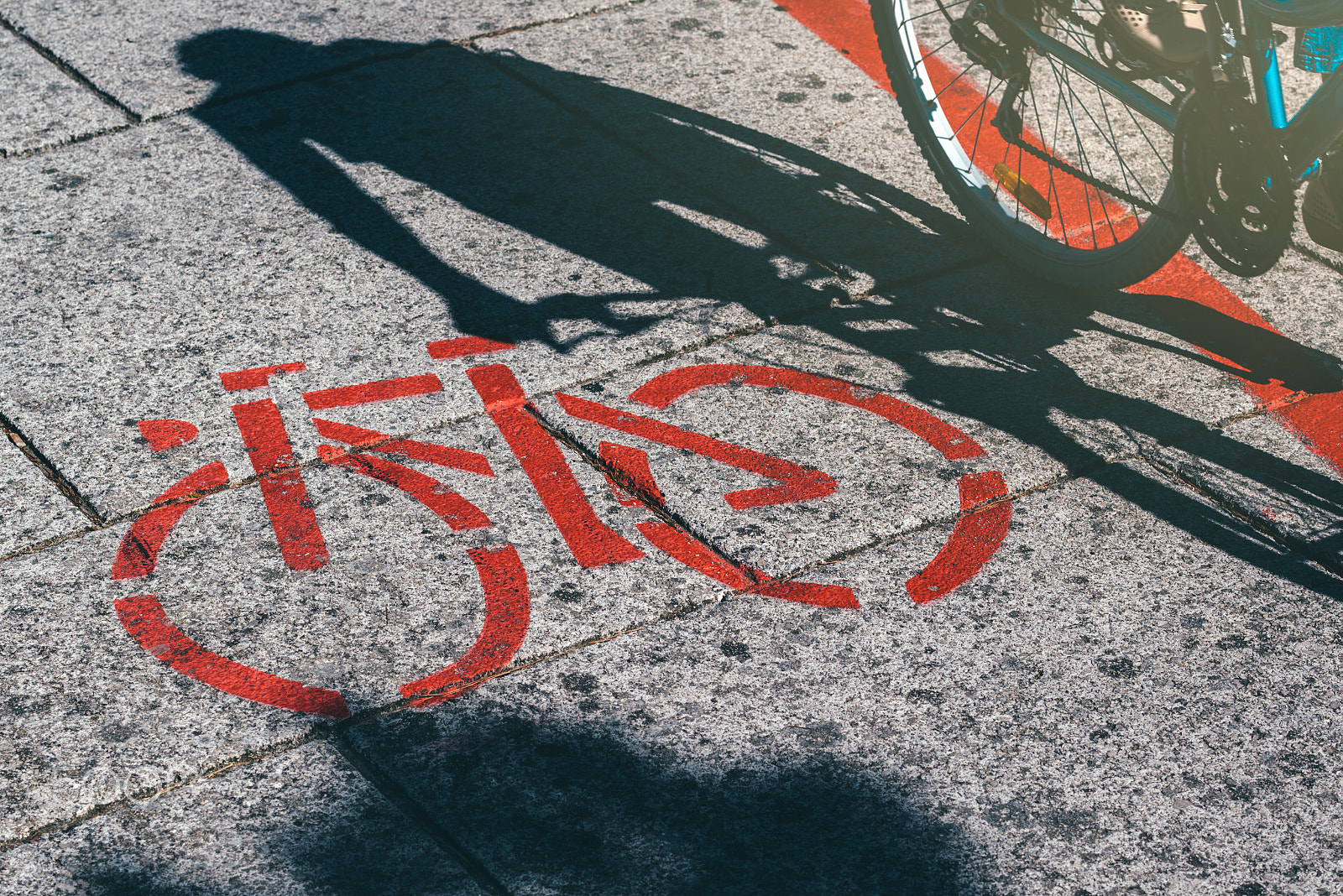 Nikon AF-S Nikkor 70-200mm F4G ED VR sample photo. Shadow of female biker and bicycle route road marking photography