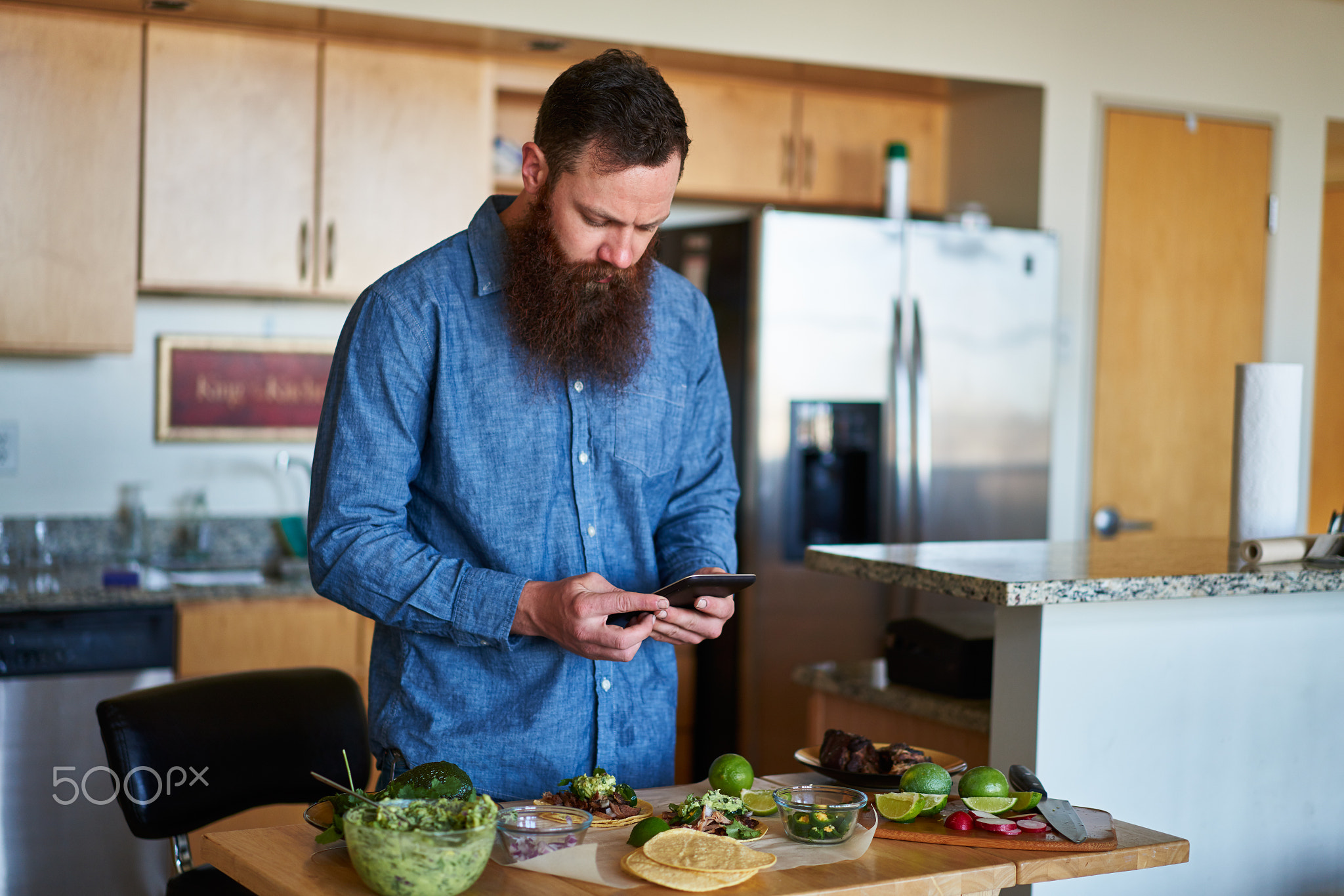 making tacos at home in kitchen and using smartphone for recipe