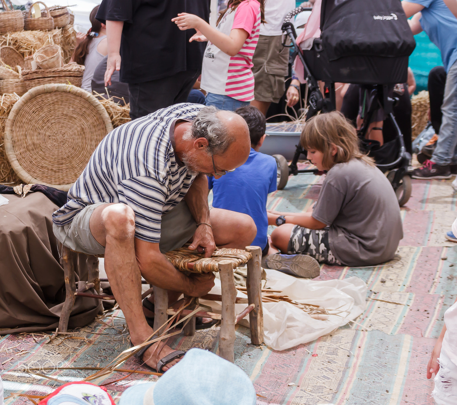 Canon EF 75-300mm F4.0-5.6 IS USM sample photo. Elderly man weaves chair at the fair photography