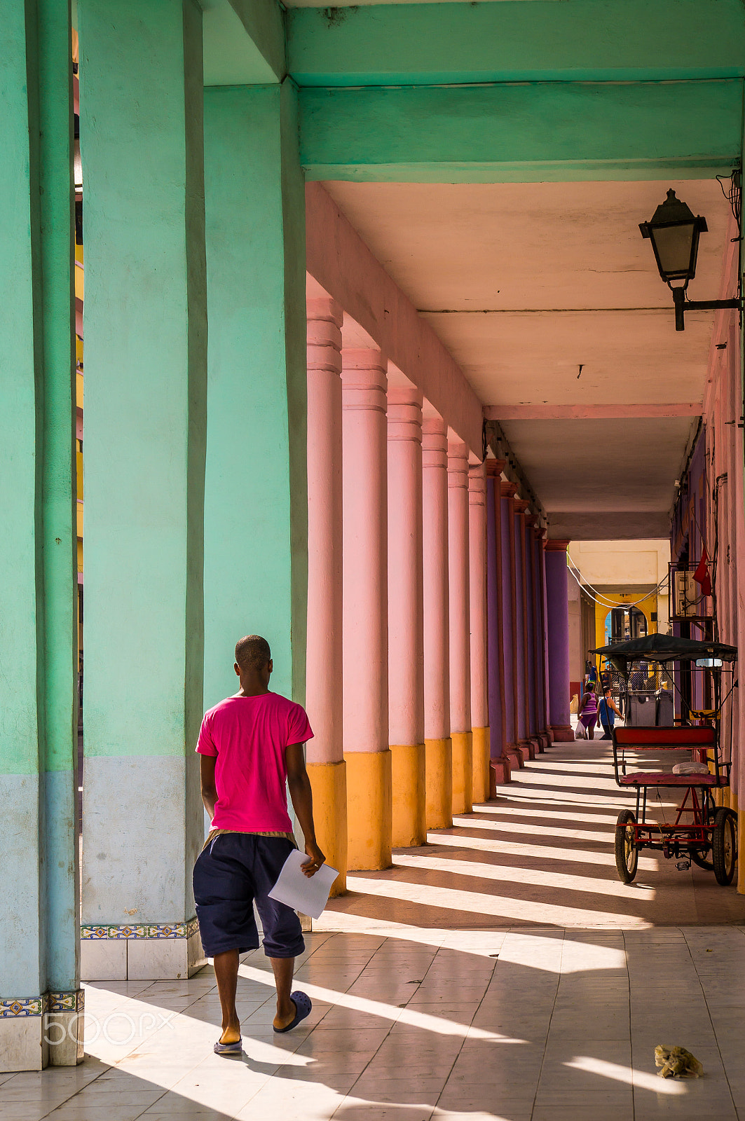 Sony SLT-A37 sample photo. Cuban man walking through colorful colonnade in havana photography