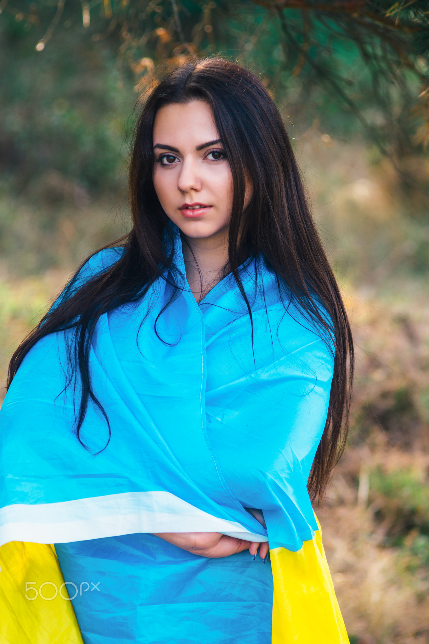 Beautiful brunette model posing in a park with flag of Ukraine