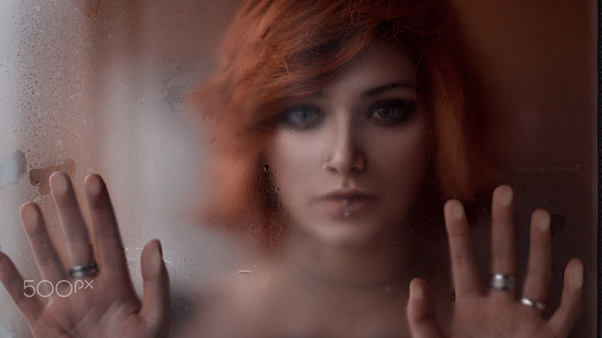 Girl with red hair standing behind the glass