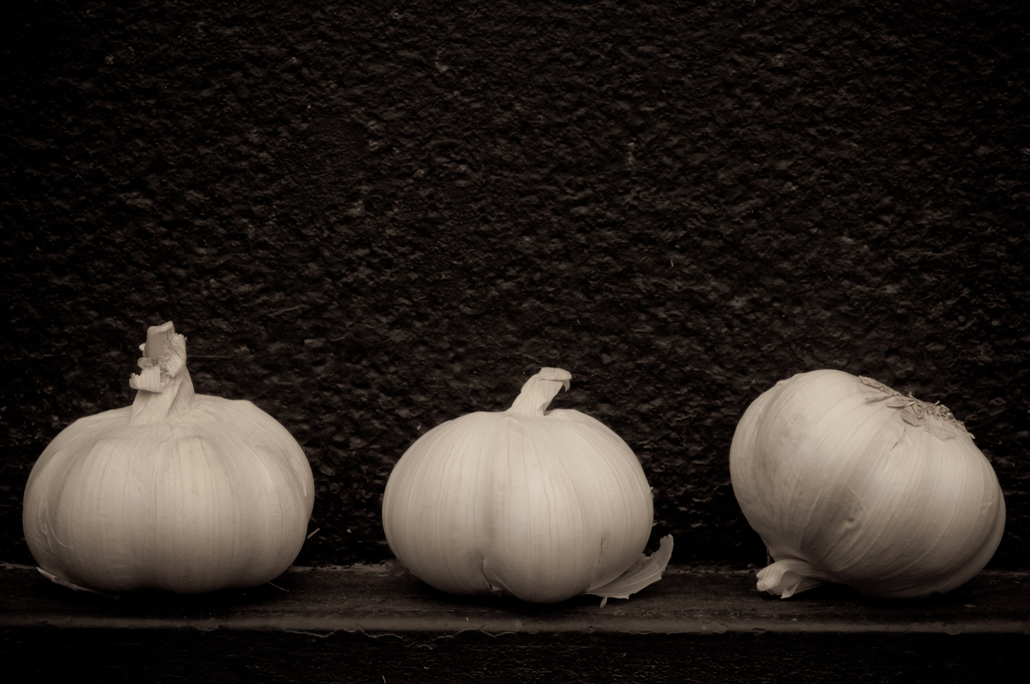 Nikon D2X sample photo. Garlic in front of rough textured black background photography