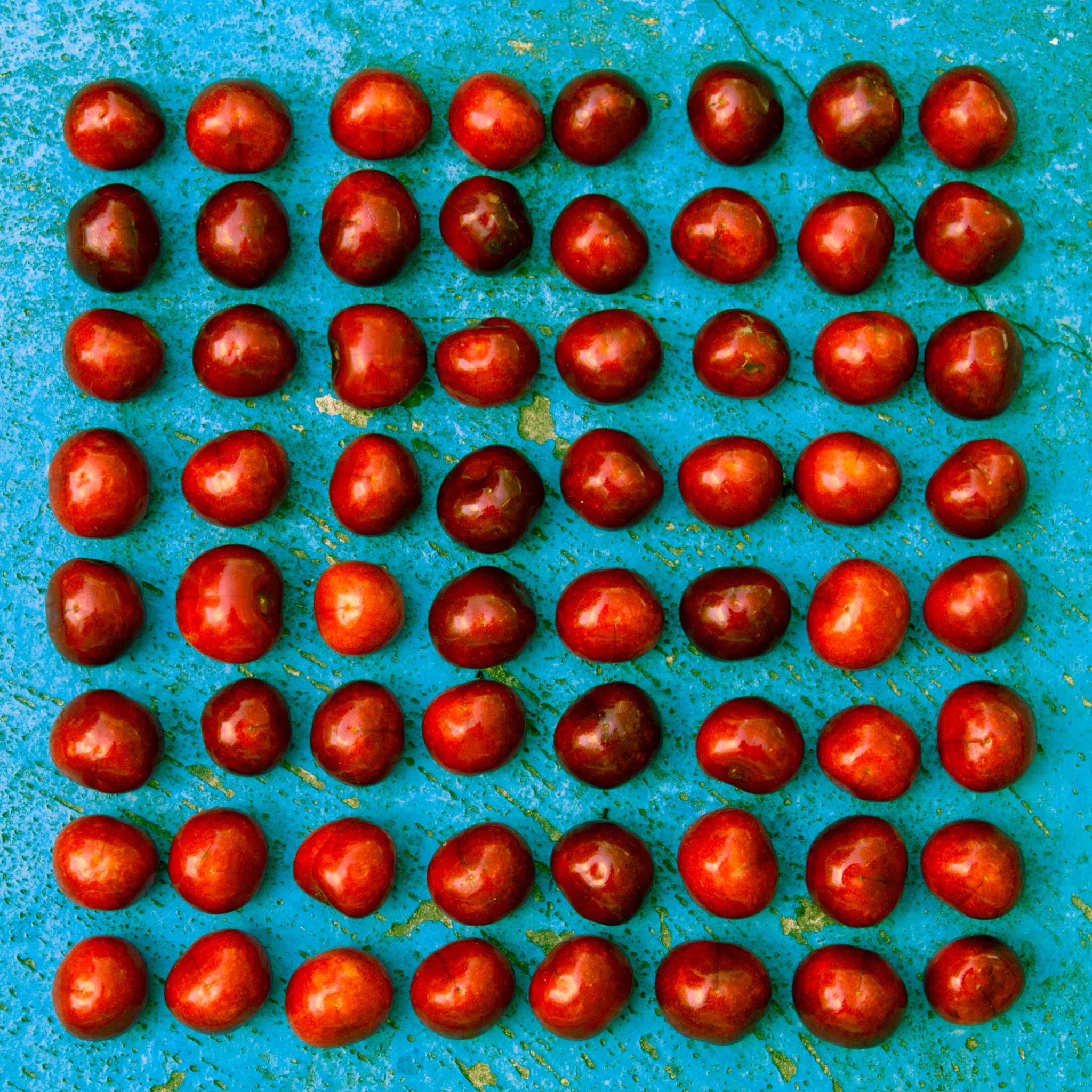 Nikon D2X sample photo. Square arrangement of ripe cherries on blue textrured background photography