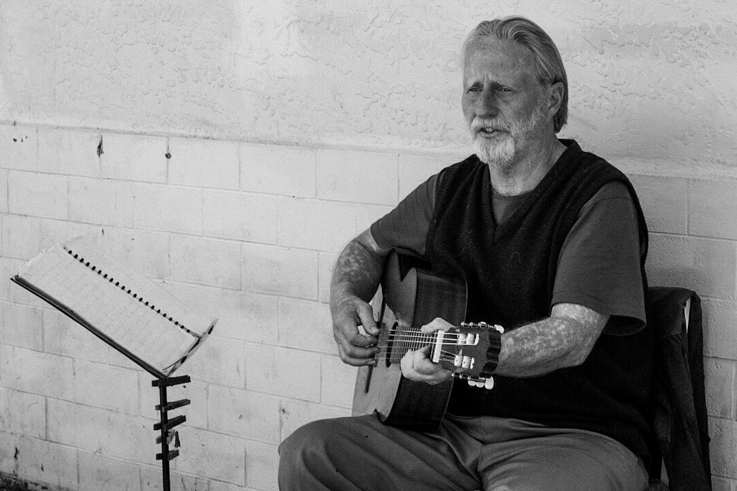 Olympus OM-D E-M1 + Olympus M.Zuiko Digital 25mm F1.8 sample photo. Busker playing guitar. good voice and soulful style. photography