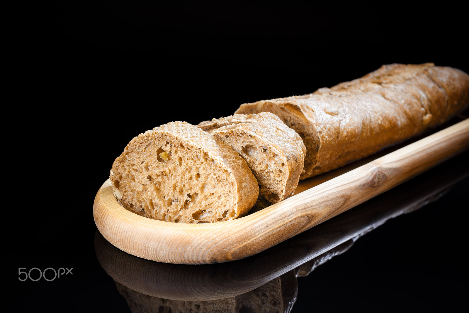 Canon EF 40mm F2.8 STM sample photo. Fresh sliced baguette on wooden oblong plate on black background photography