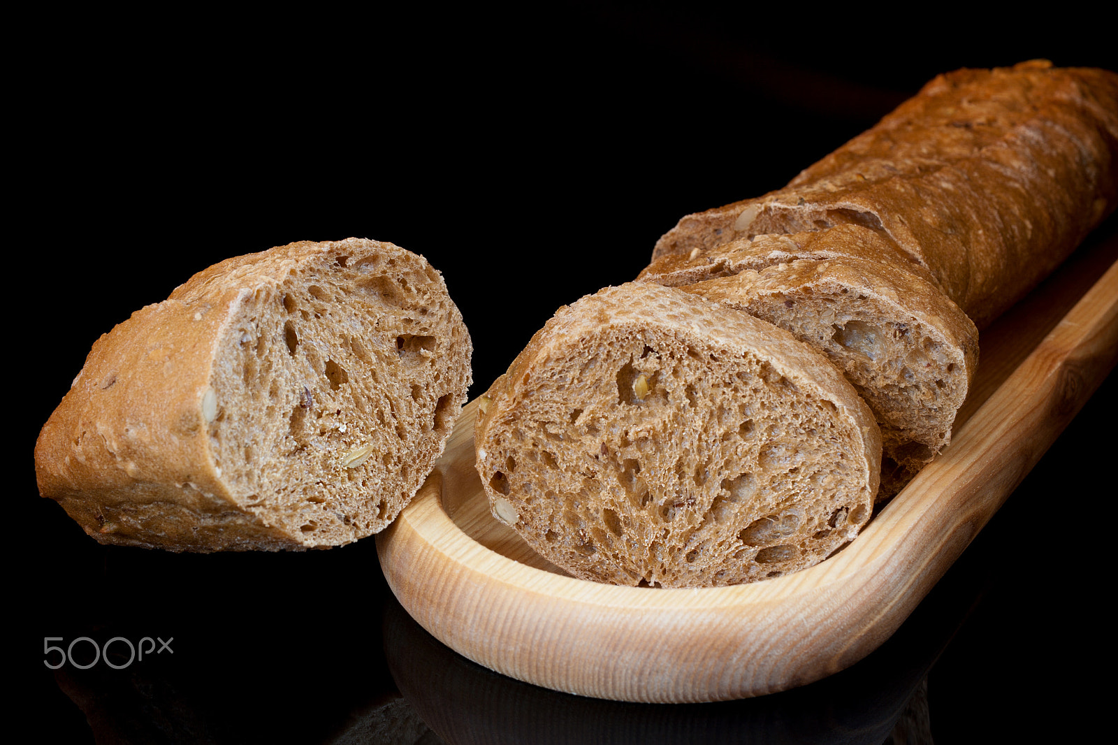 Canon EF 40mm F2.8 STM sample photo. Sliced baguette on wooden plate and crust on black photography