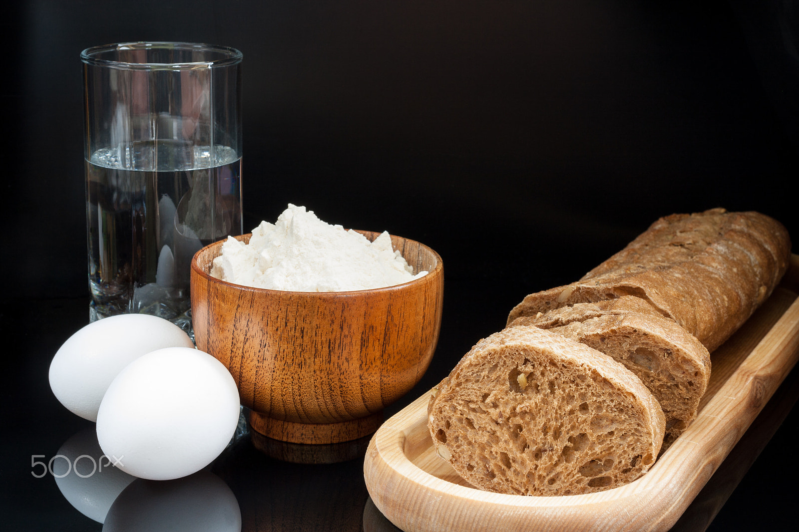 Canon EF 40mm F2.8 STM sample photo. Flour, eggs, glass of water with fresh sliced baguette on black photography