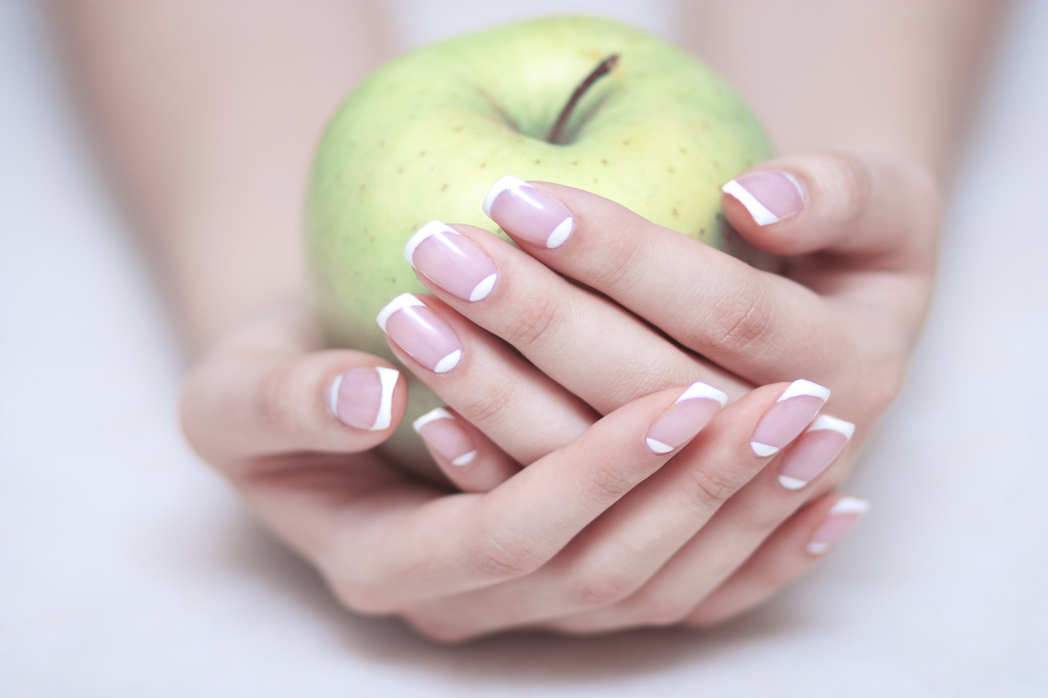 Canon EOS 450D (EOS Rebel XSi / EOS Kiss X2) + Canon EF 85mm F1.8 USM sample photo. Green apple in woman's hands with french manicure photography