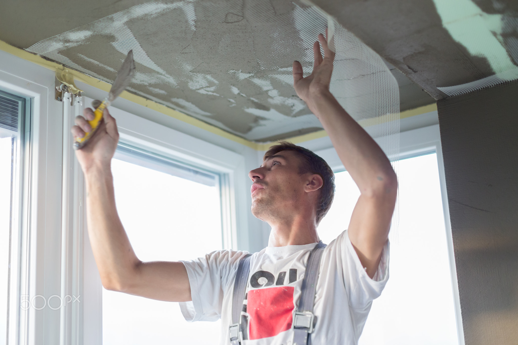 Plasterer renovating indoor walls and ceilings. Finishing works.