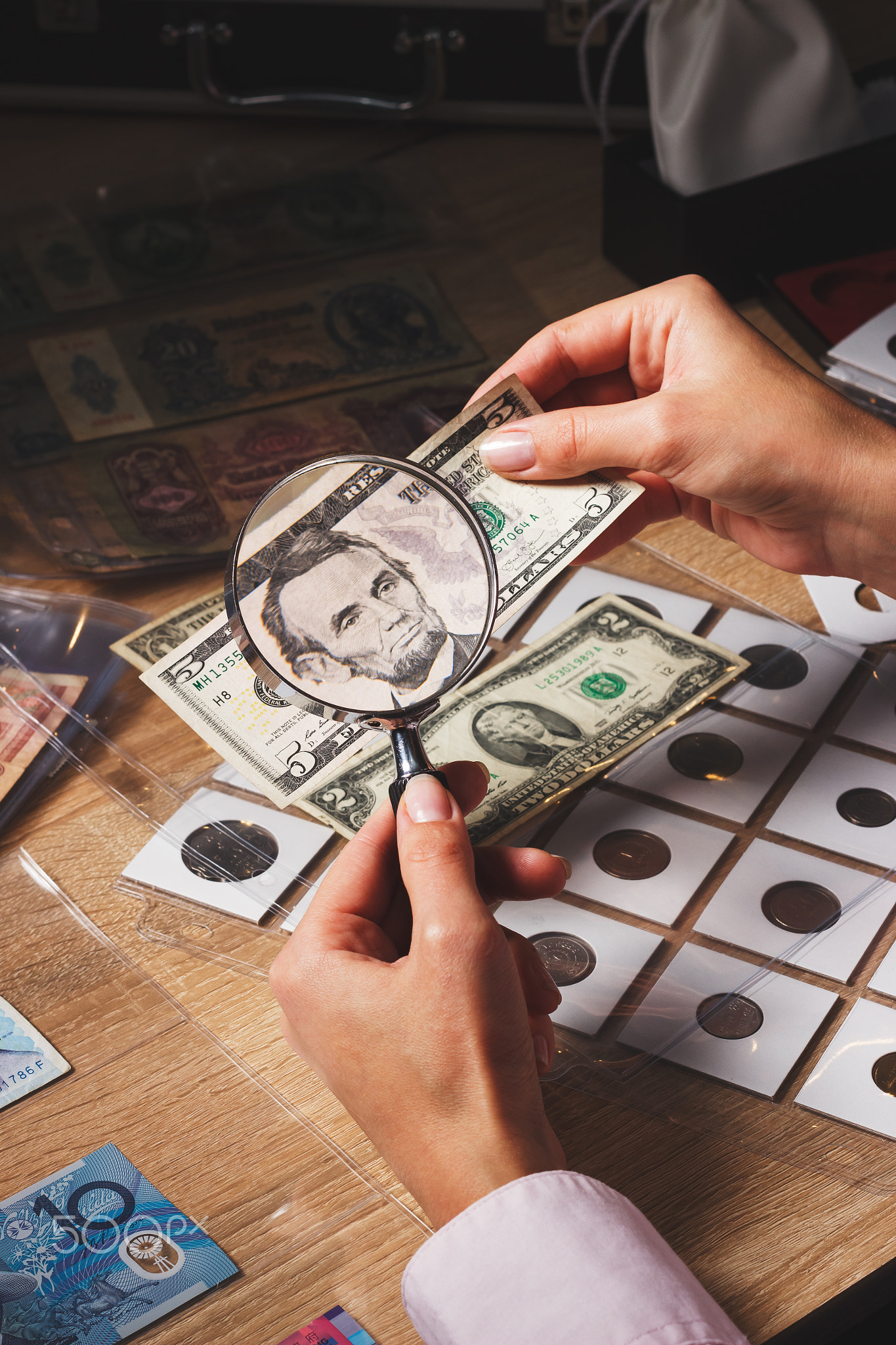 Woman looks at the Dollar bill through a magnifying glass