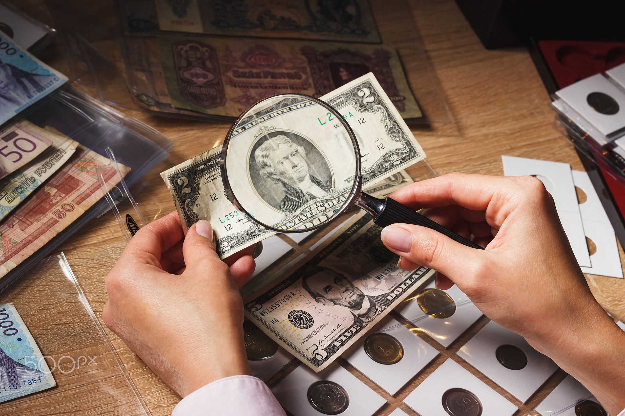 Woman looks at the Dollar bill through a magnifying glass