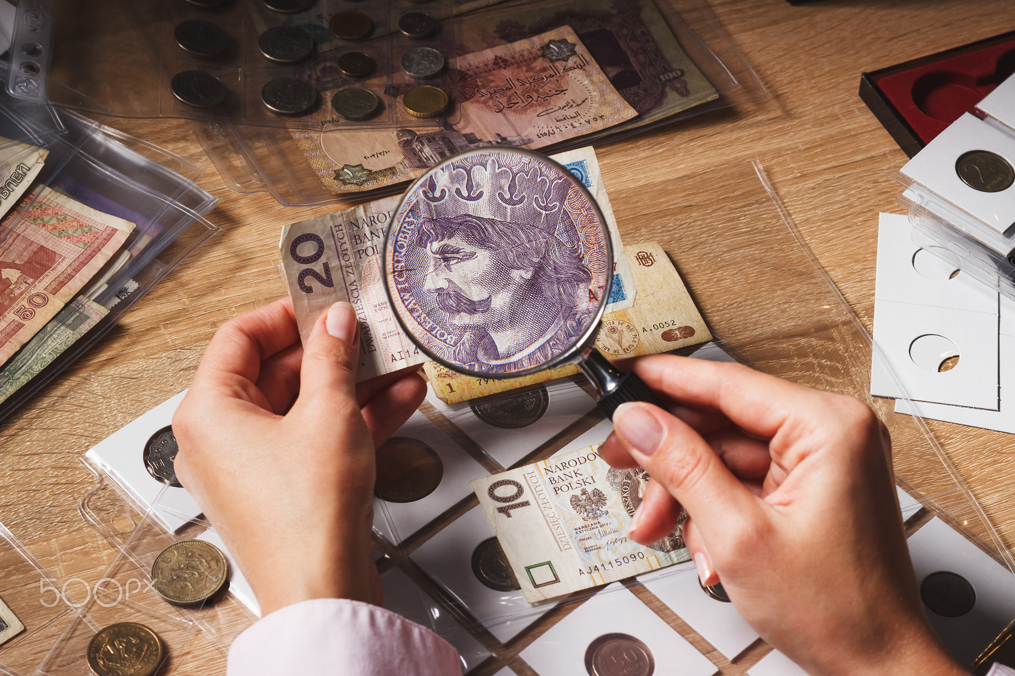 Woman looks at the Zloty bill through a magnifying glass