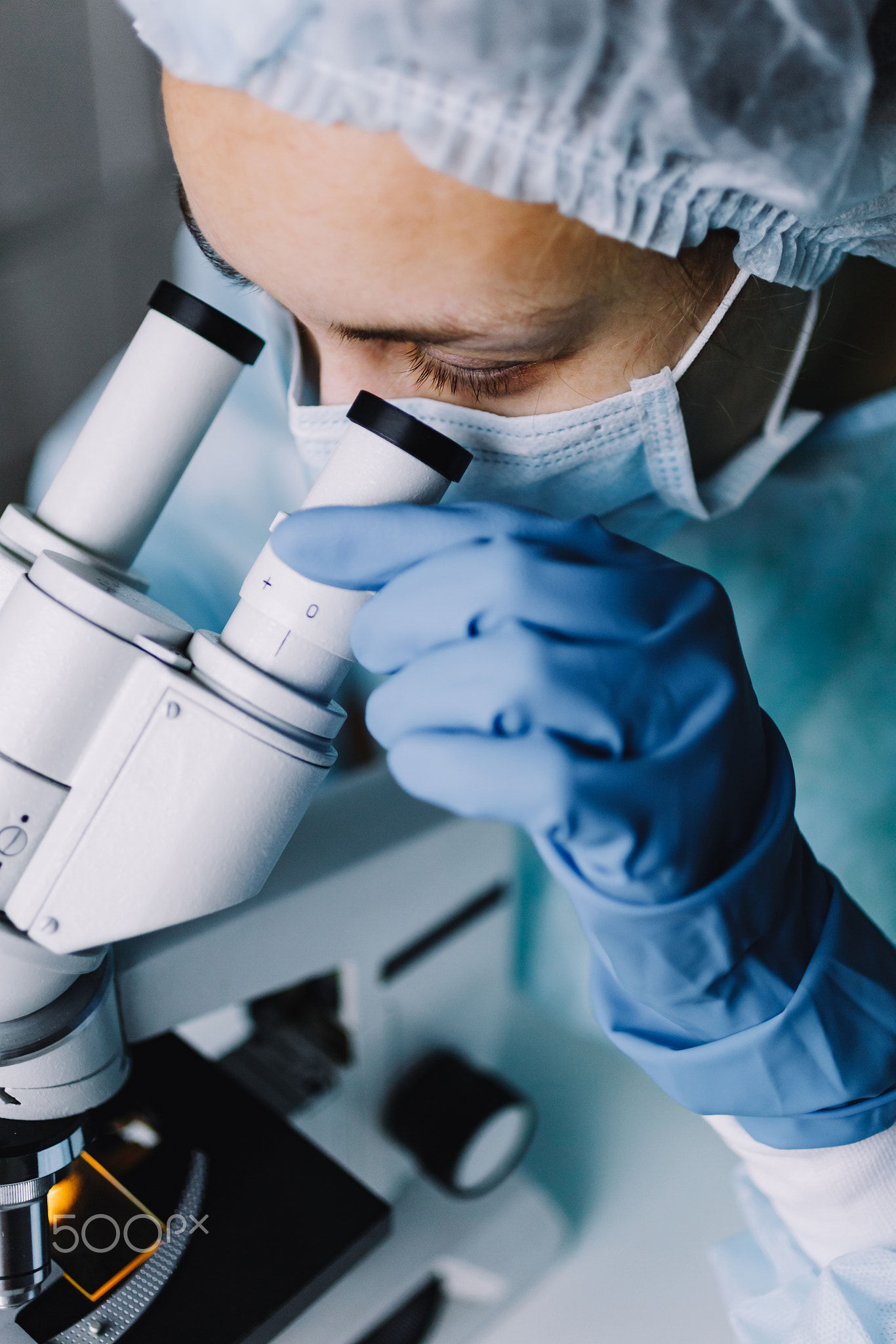Young scientist in uniform looking at microscope
