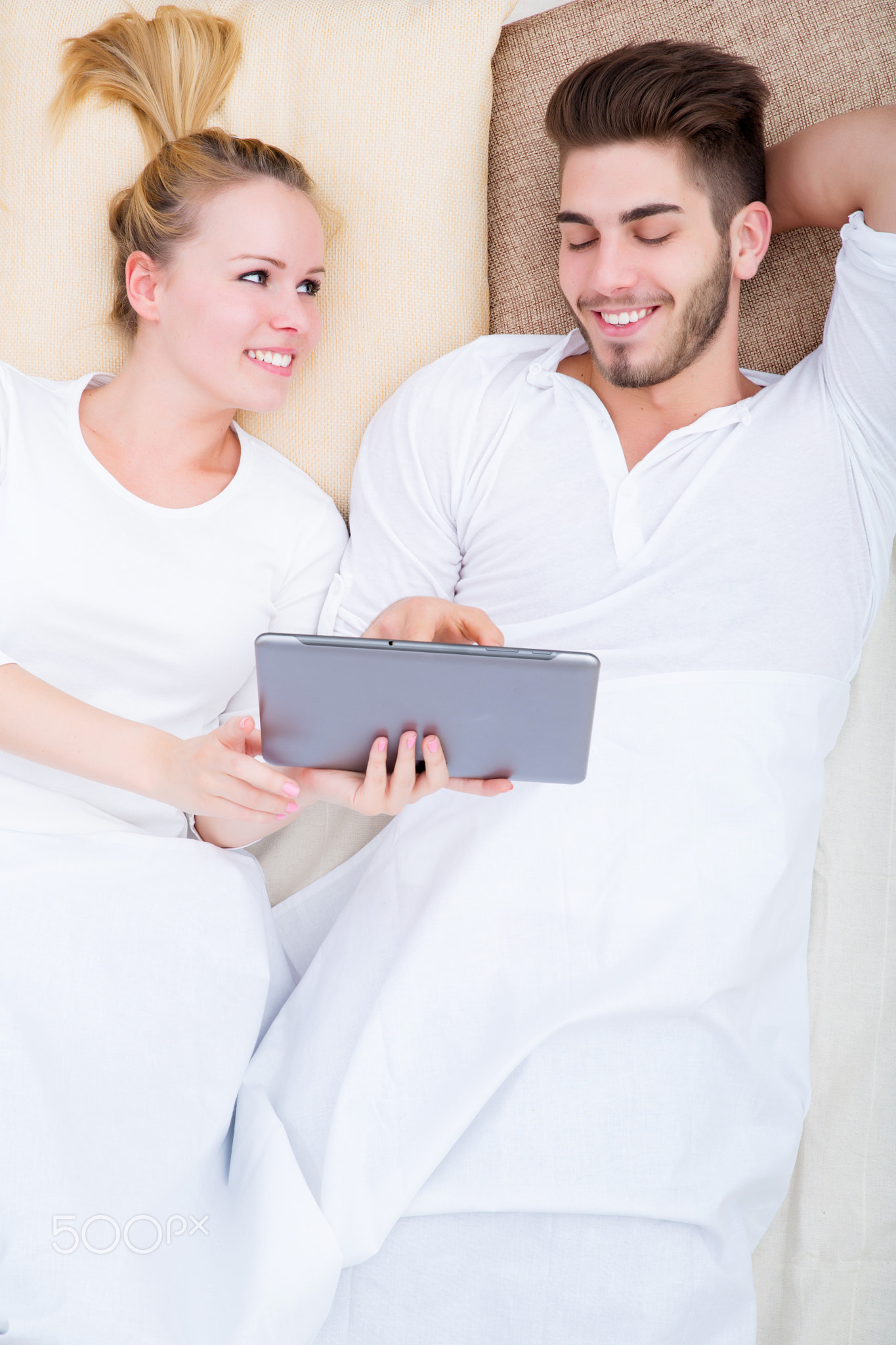 Young couple with a tablet PC in bed