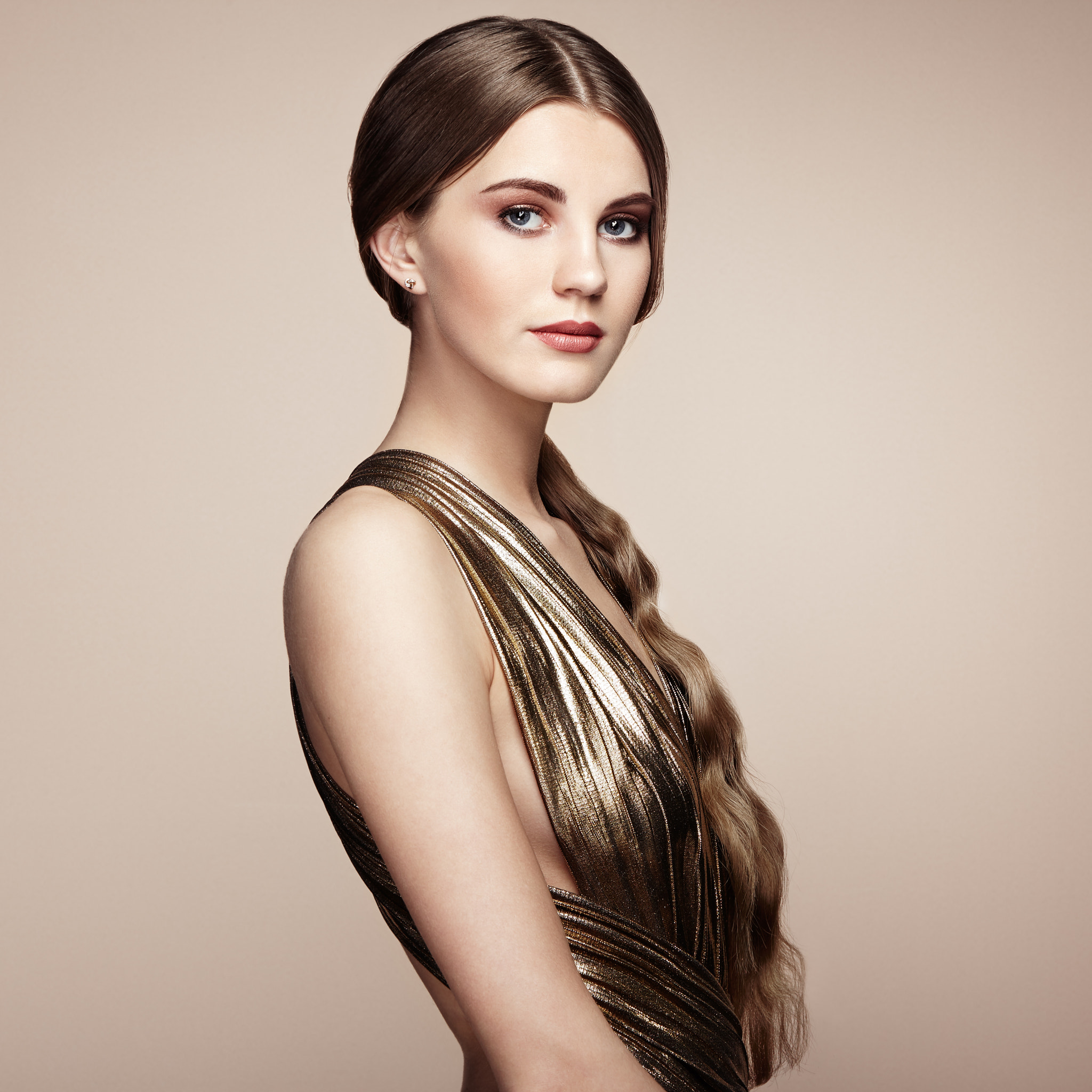 Fashion portrait of young beautiful woman in gold dress