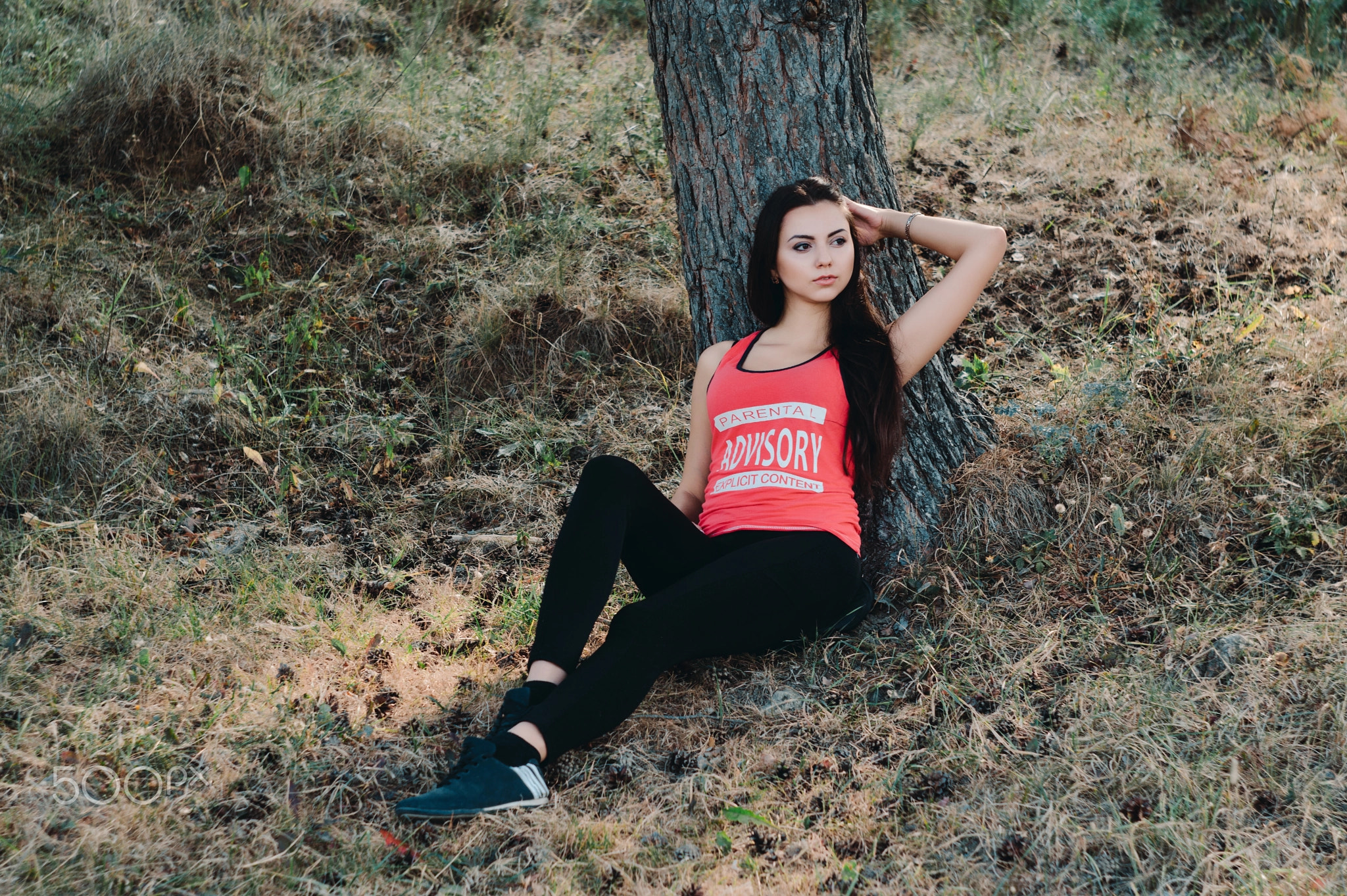 Young beautiful brunette model posing in the sports image of the park against the backdrop trees