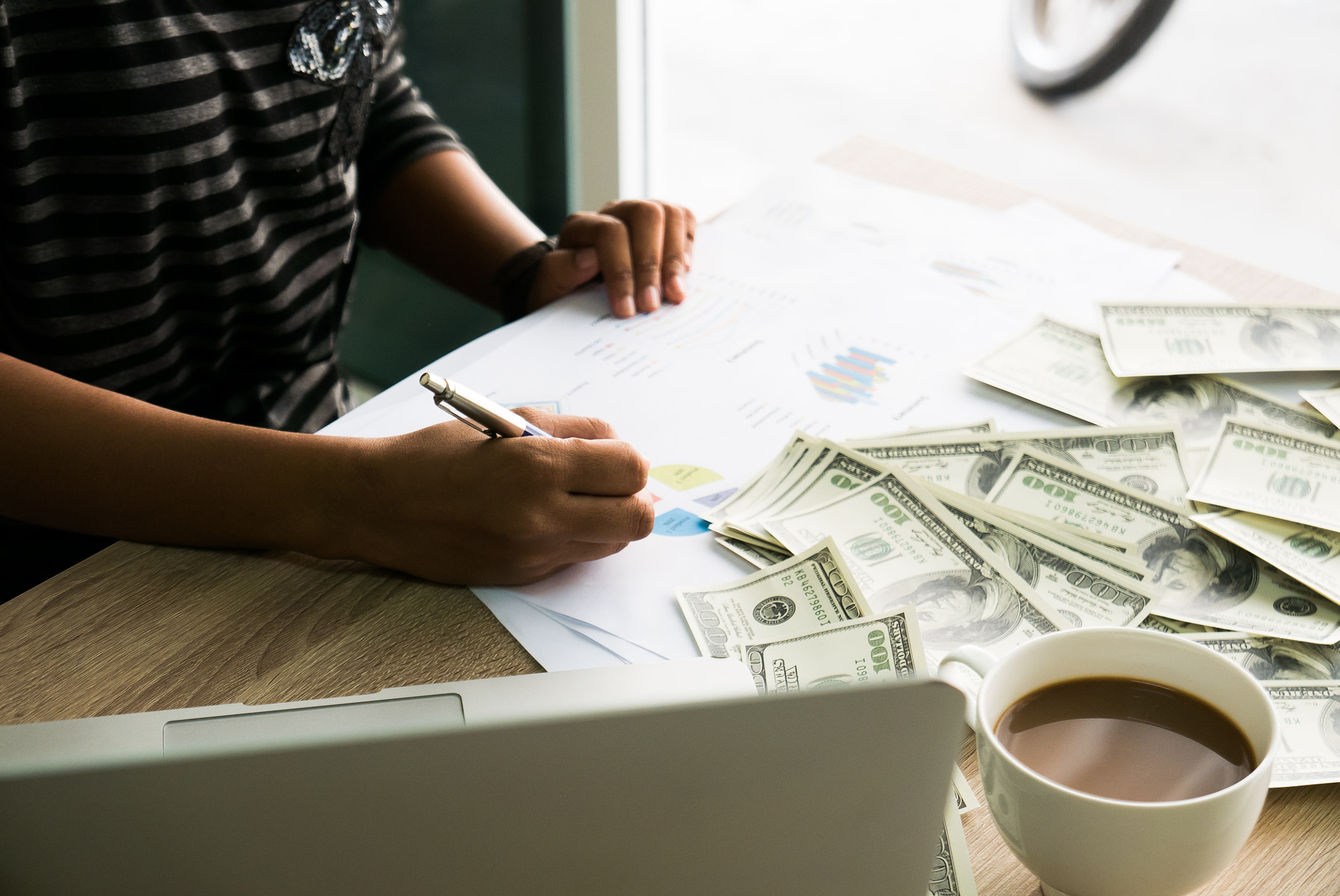 Closeup of Asian female writes something on business charts unde