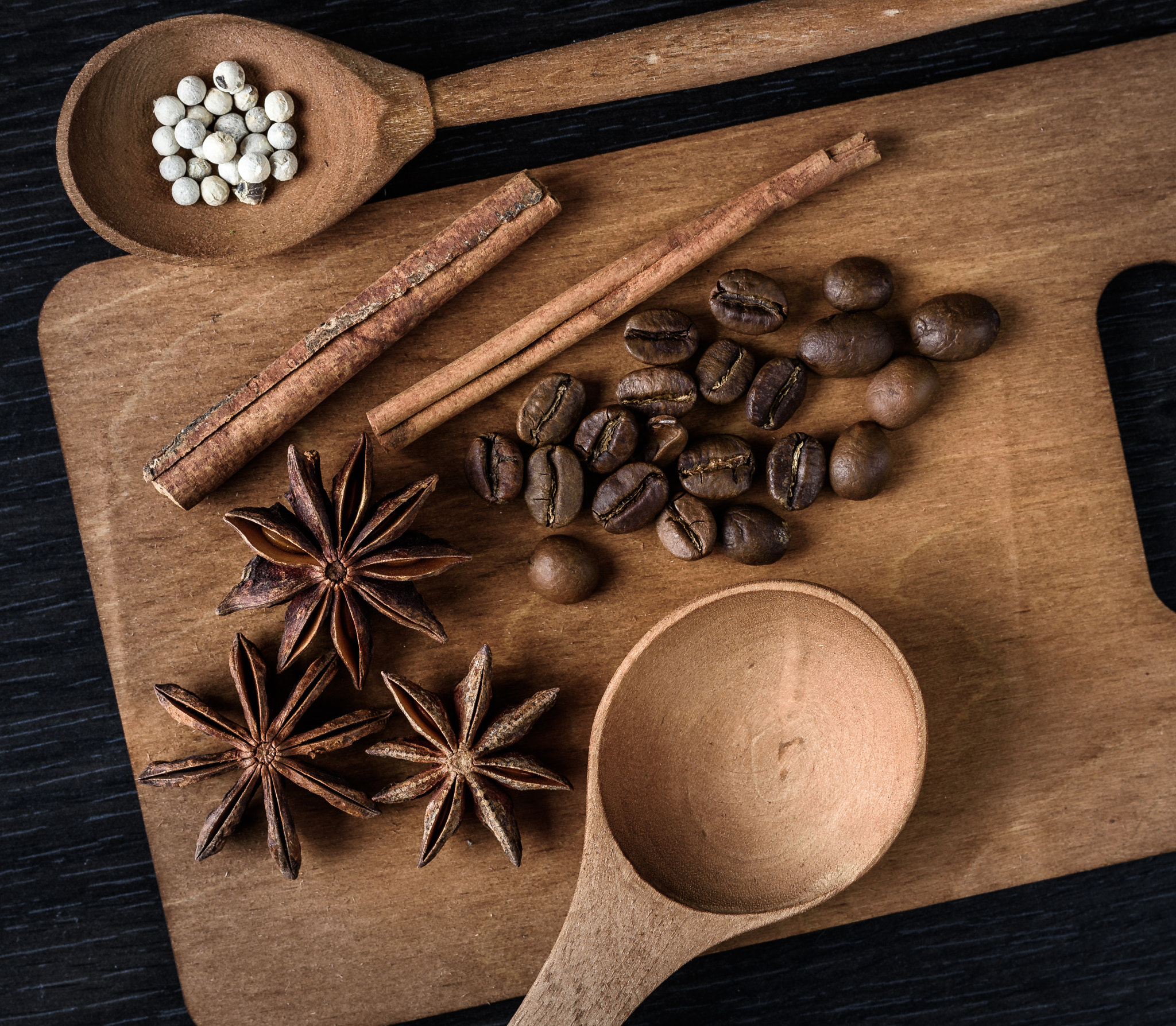 coffee, star anise, cinnamon, spoon on wooden cutting Board and dark background