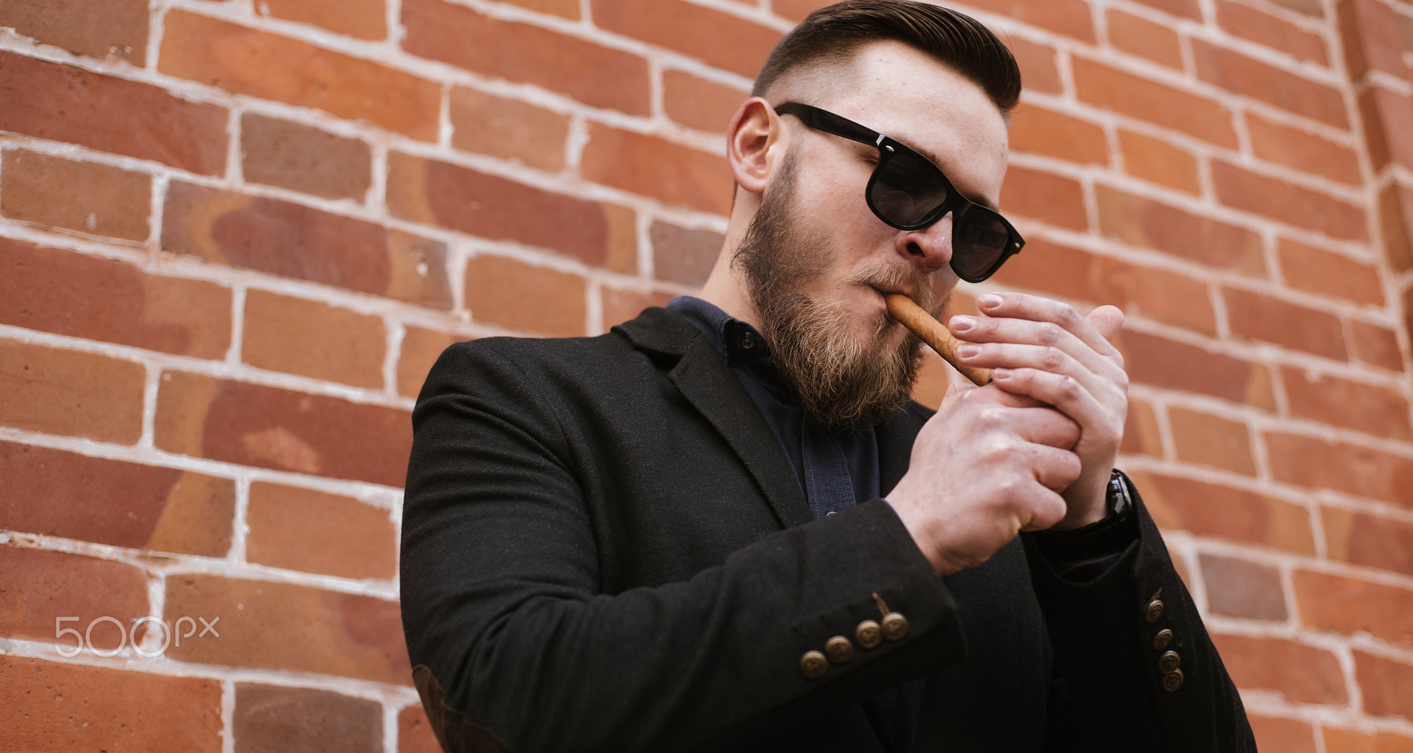 Side view of handsome bearded man smoking a cigar