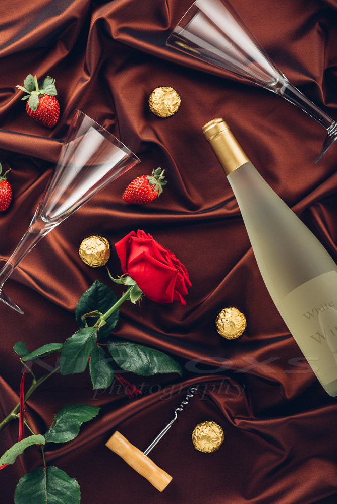 Rose, wine,  petals and strawberry on satin fabric