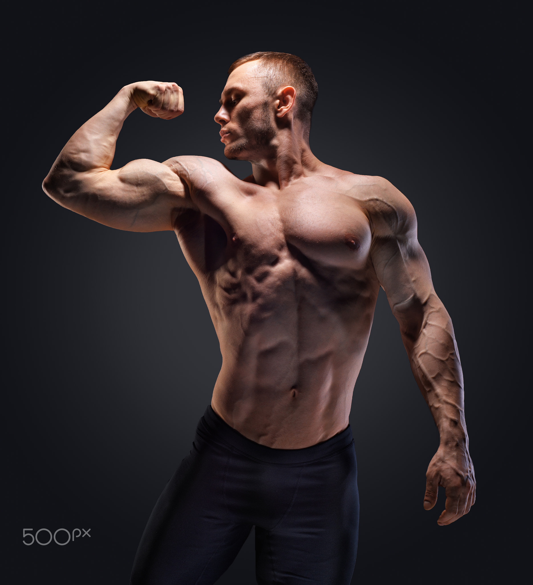 Muscular shirtless man in studio over dark background show his muscle.