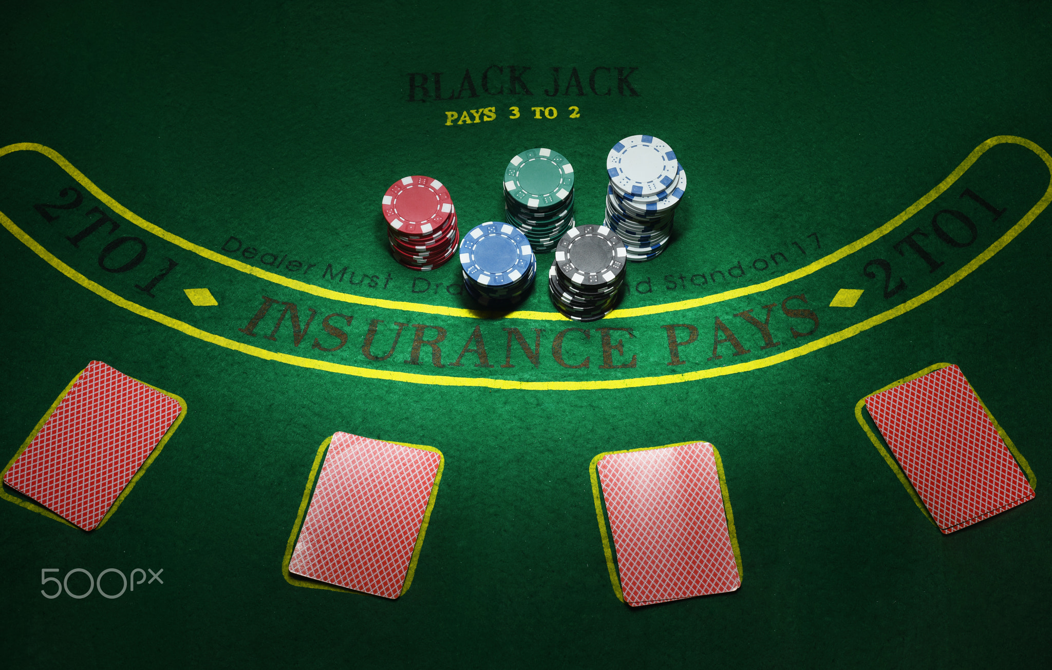 Cards and chips for poker on green table, top view