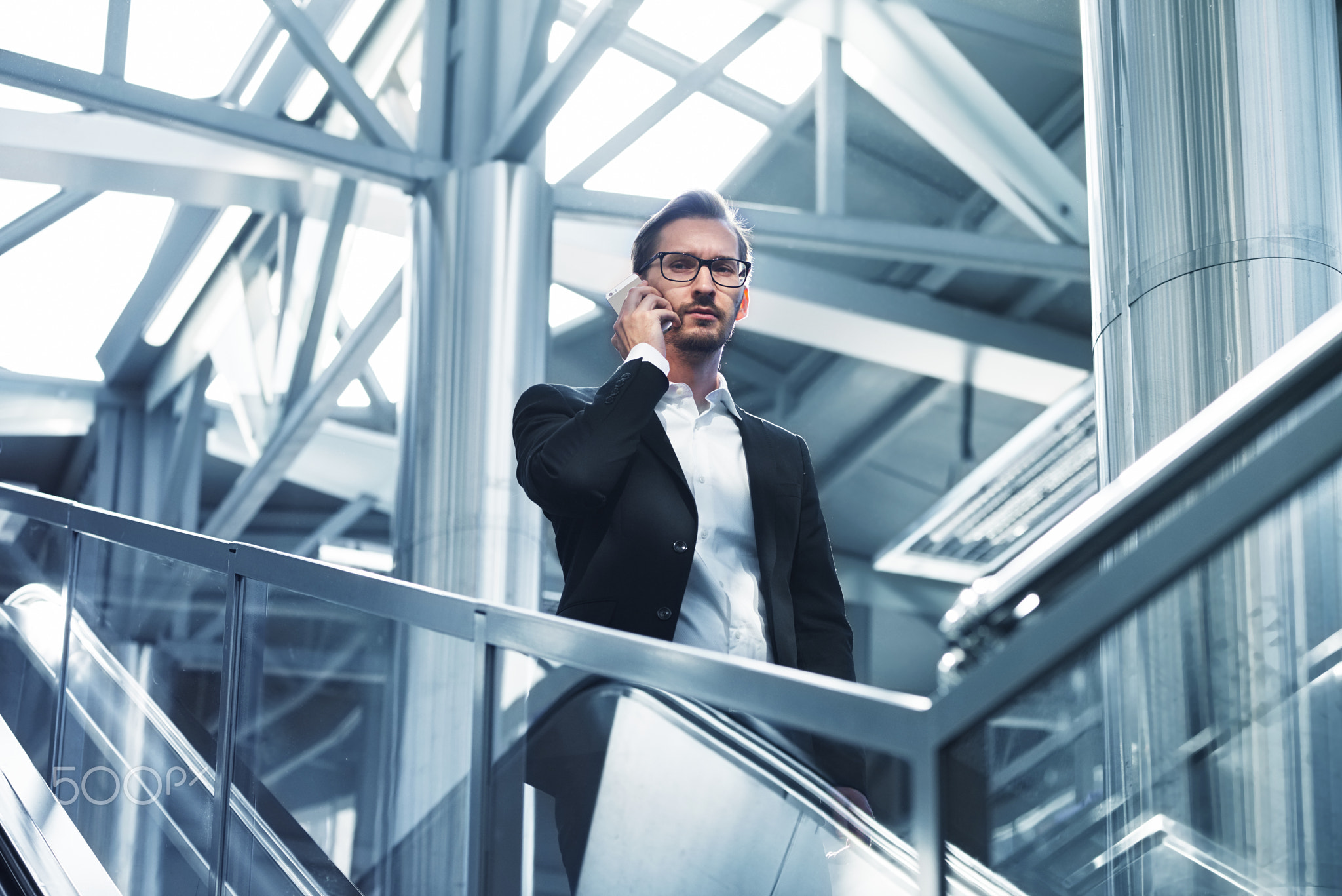 Man on smart phone - young businessman in airport. Handsome serious men wearing suit jacket indoors