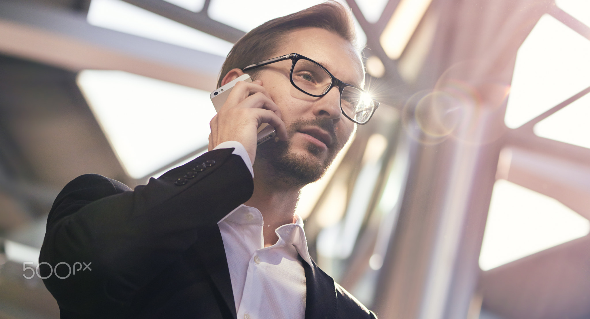 Portrait of handsome businessman in suit and eyeglasses speaking on the phone in airport