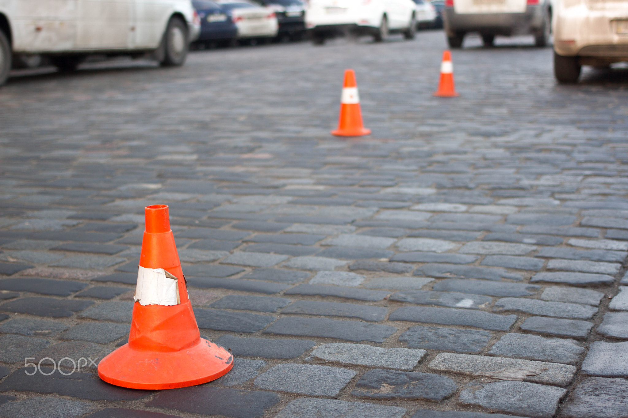 Traffic cone stay on paving stone  street. Limit for parking
