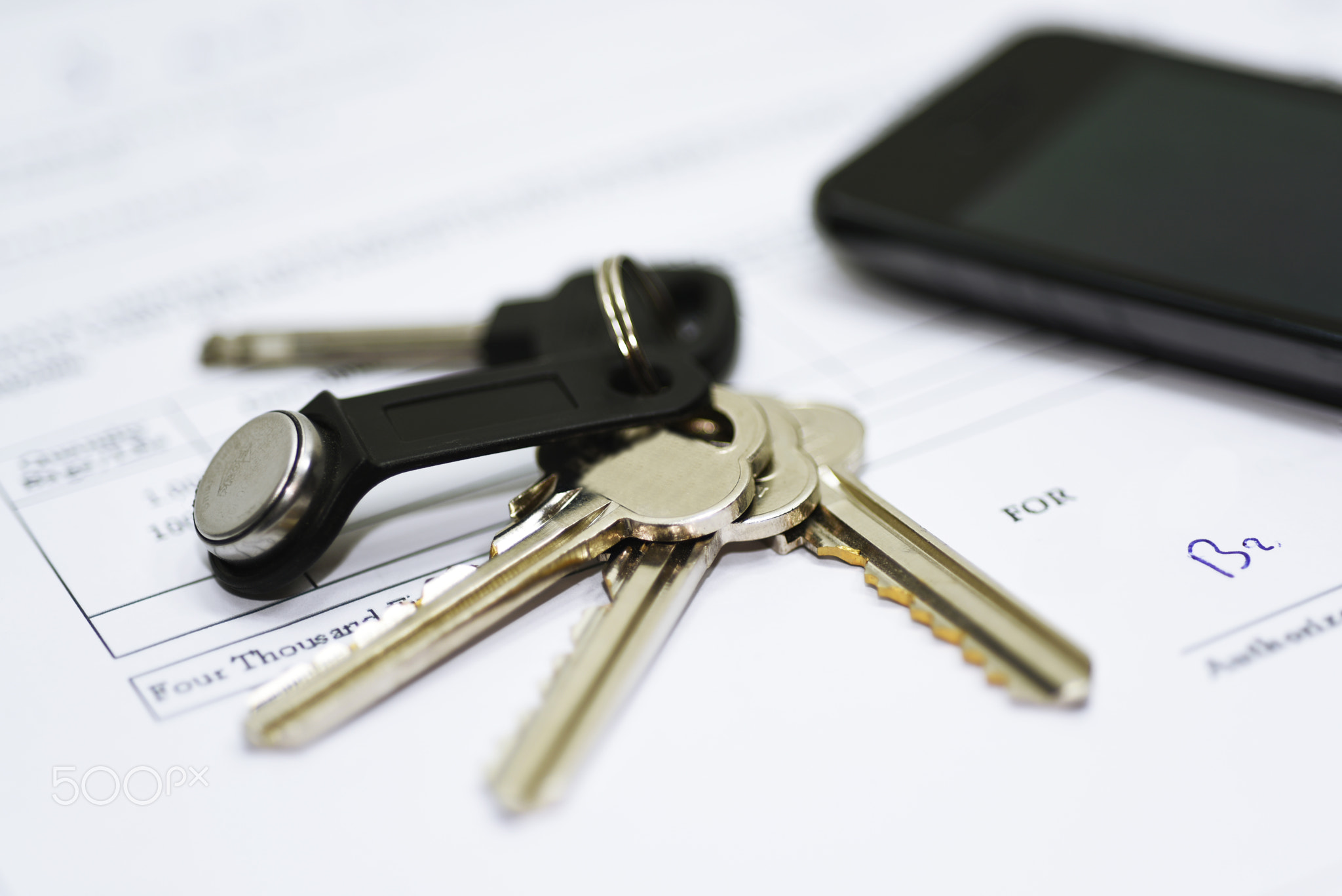 House keys on documents with mobile phone