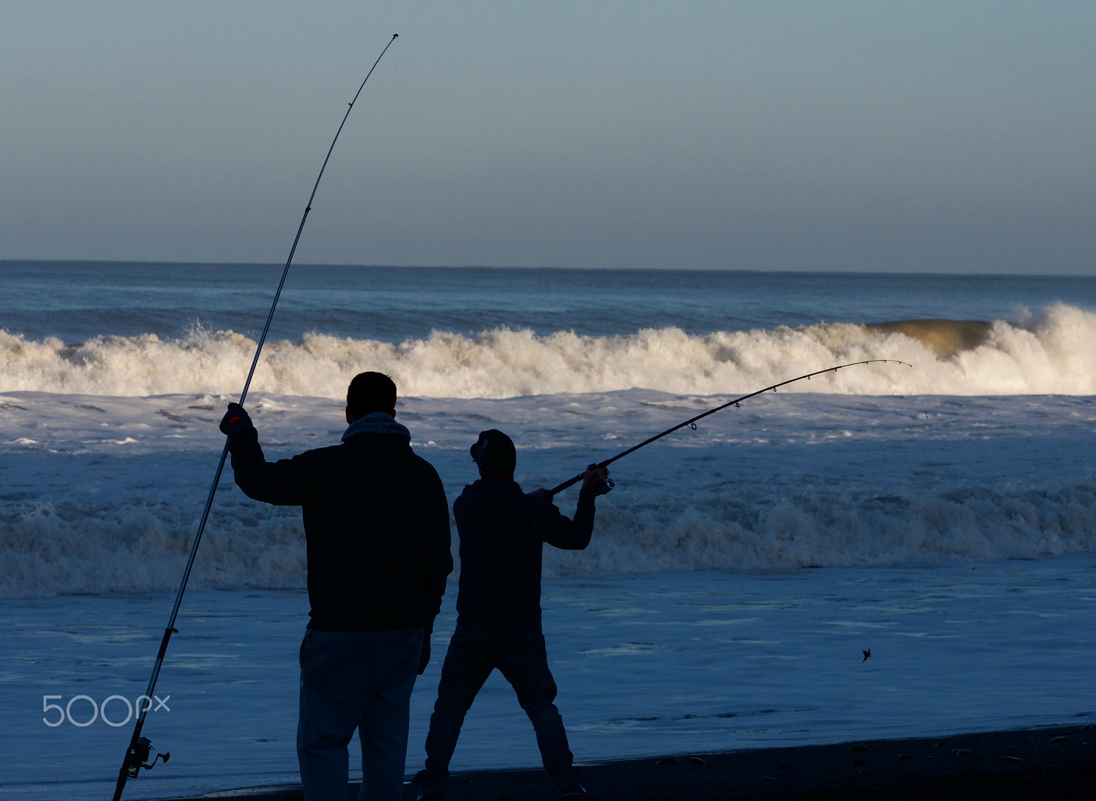 Panasonic Lumix G X Vario 35-100mm F2.8 OIS sample photo. Beach fisherman casting rod into surf photography