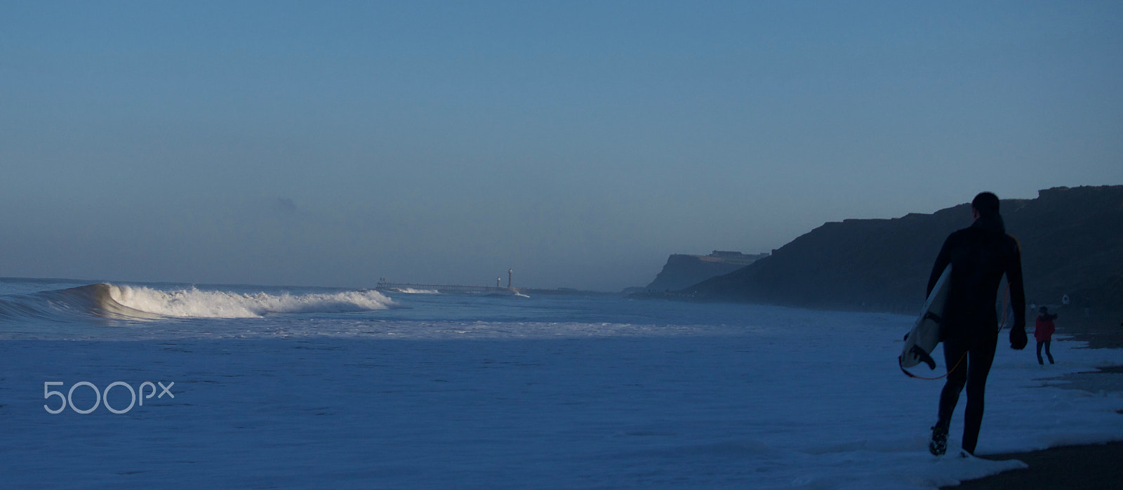 Panasonic Lumix DMC-G7 + Panasonic Lumix G X Vario 35-100mm F2.8 OIS sample photo. Surfer walking along a winter beach photography