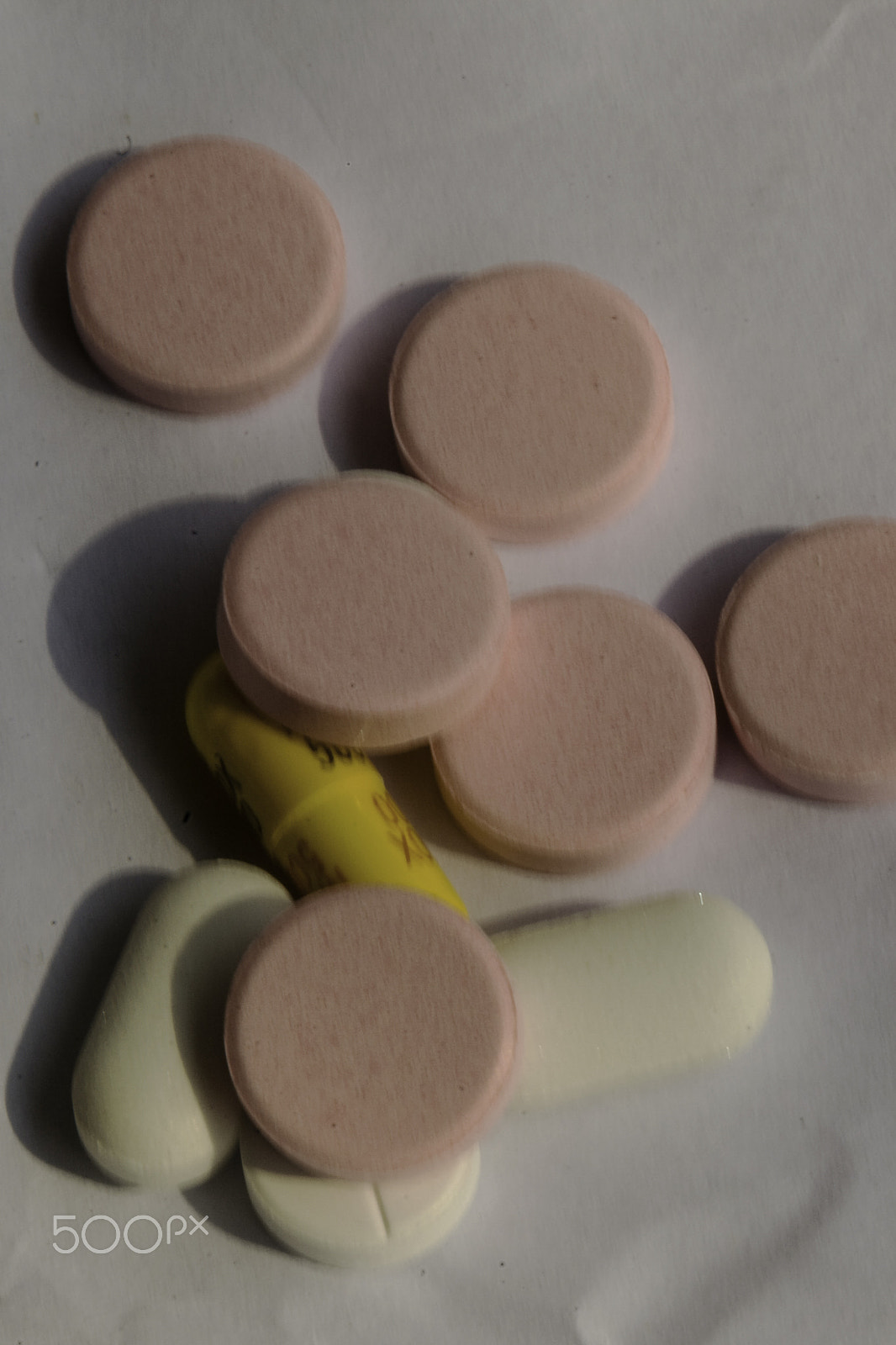 Canon EF 100mm F2.8 Macro USM sample photo. Pink and white tablets covering a yellow capsule on a white back photography
