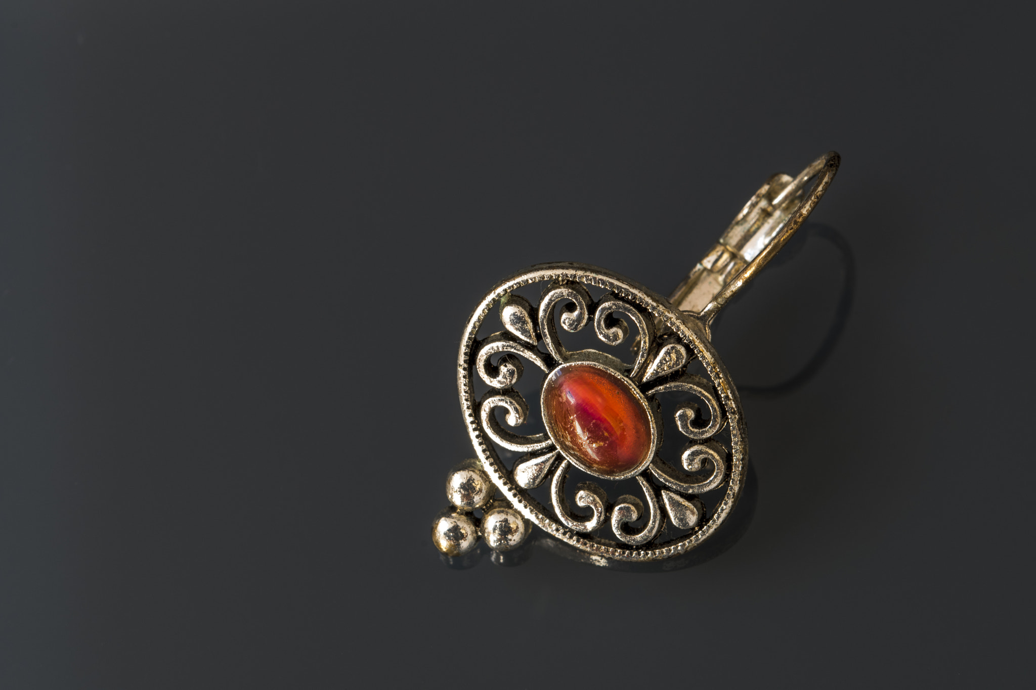 Sigma 105mm F2.8 EX DG OS HSM sample photo. Silver earrings with red gems on dark background with reflection photography