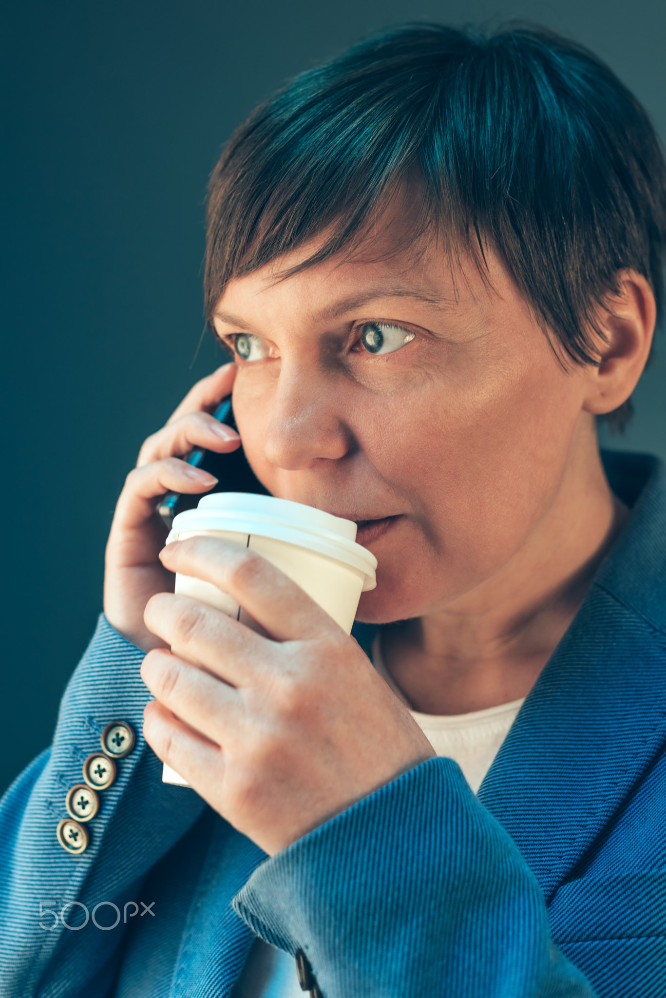 Businesswoman drinking coffee to go and talking on mobile